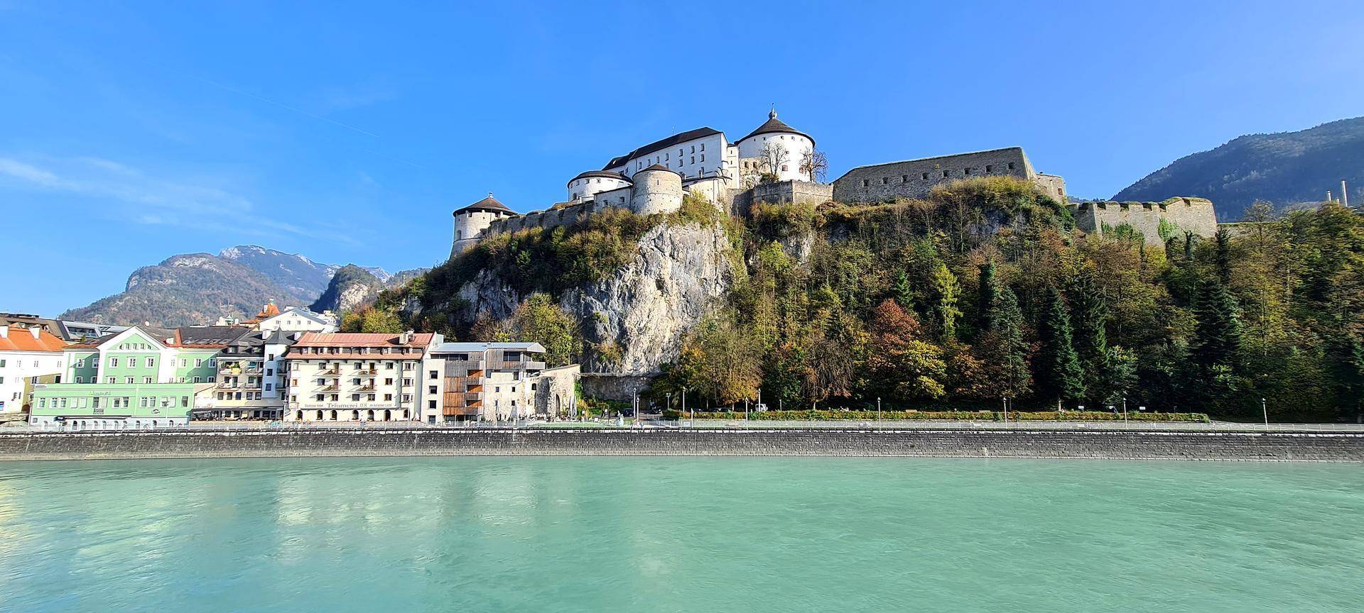 Historische Festung auf einem Felsen über dem Fluss mit umliegender Stadtkulisse.