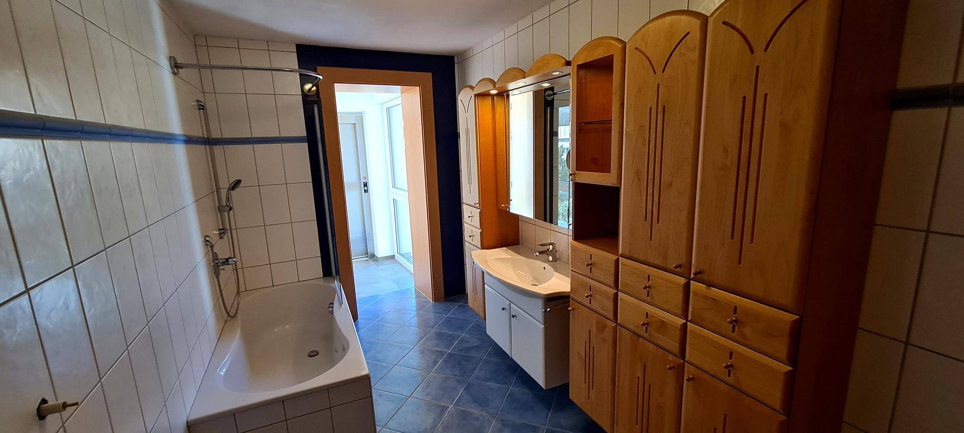 Badezimmer mit Badewanne, Dusche und Holzschränken im traditionellen Stil.