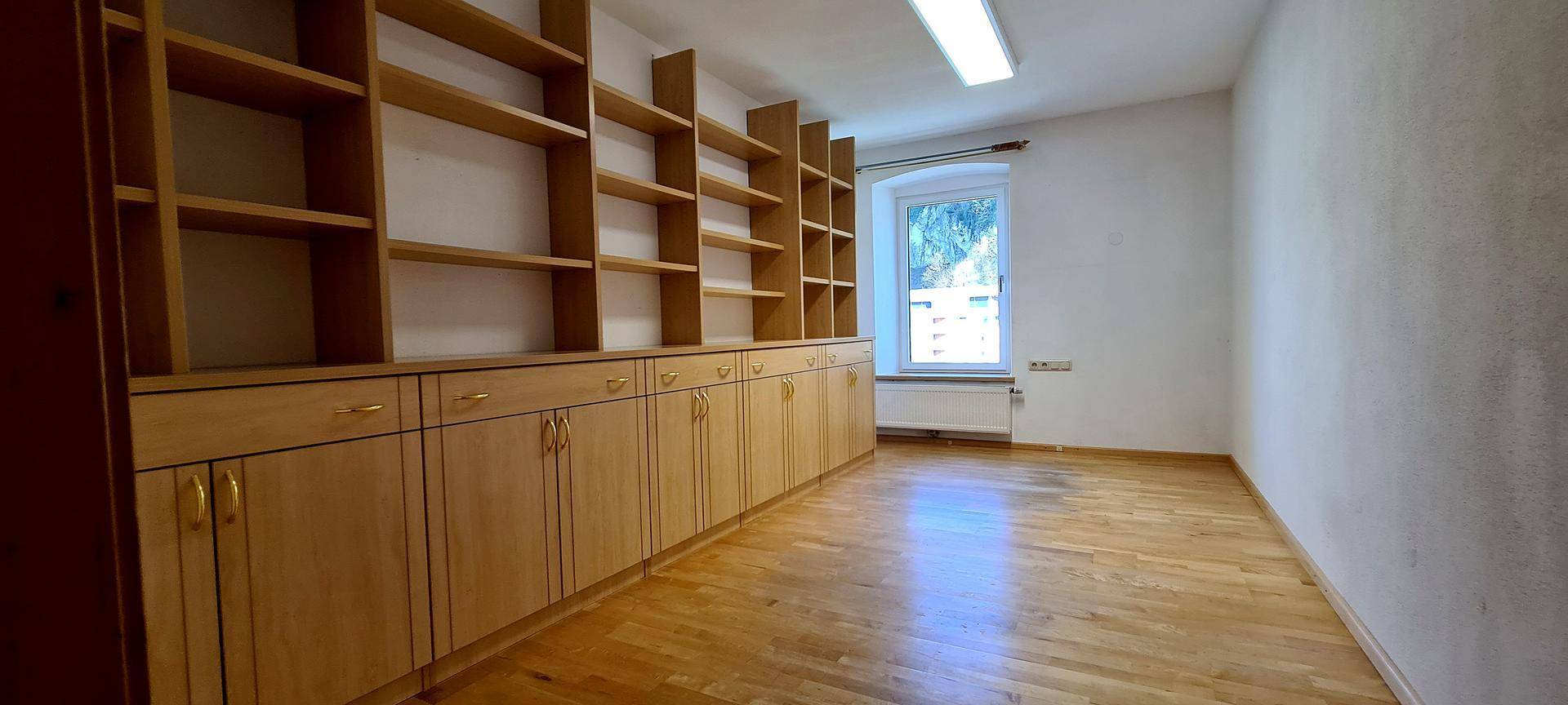 Arbeitszimmer mit großen Holzregalen und Schränken, ideal für eine Bibliothek.
