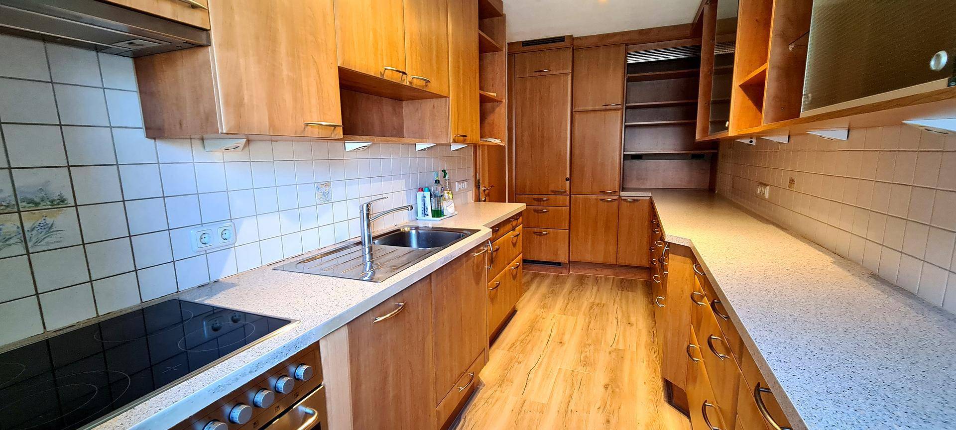 Geräumige Küche mit Holzfronten, Fliesenrückwand und integrierten Geräten.