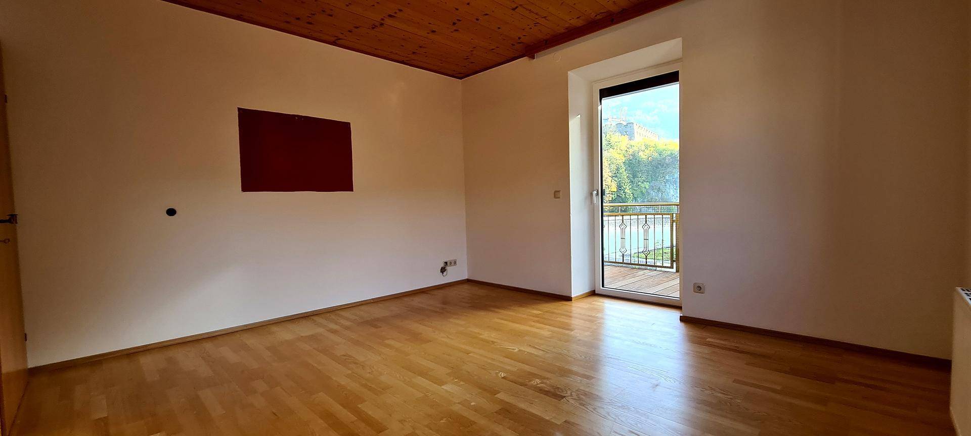 Schlafzimmer mit Parkettboden und Zugang zu einem französischen Balkon.
