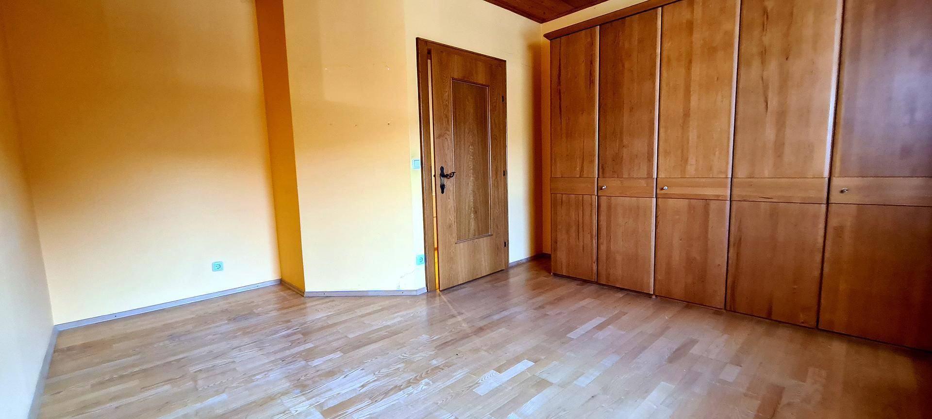 Schlafzimmer mit Parkettboden und Einbauschränken aus Holz, bereit zur Einrichtung.