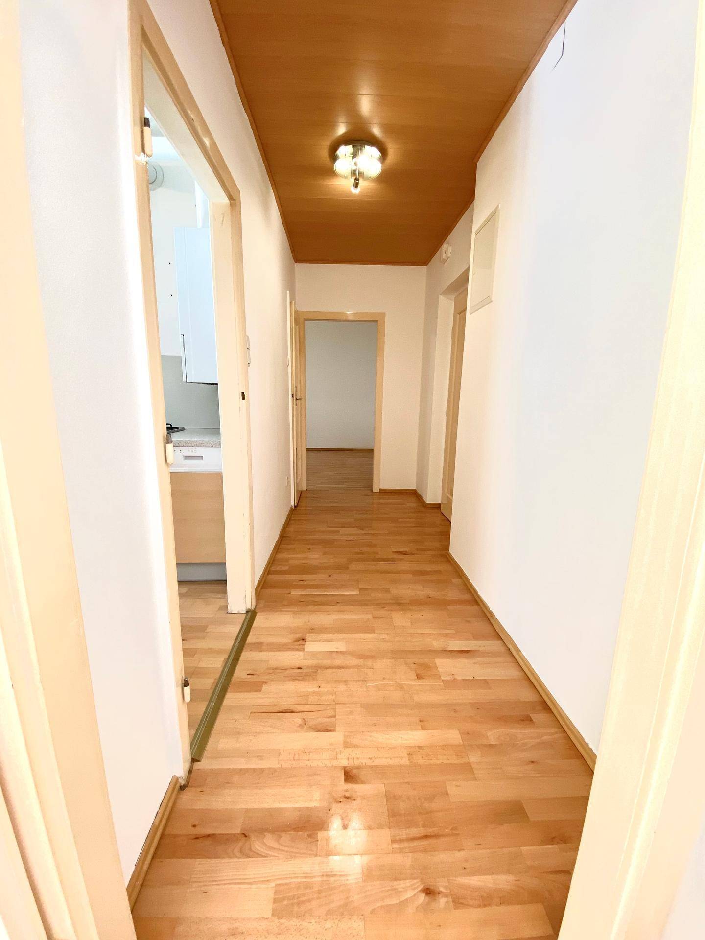 Heller Flur mit Parkettboden und einer Holzdecke, der zu weiteren Räumen führt.