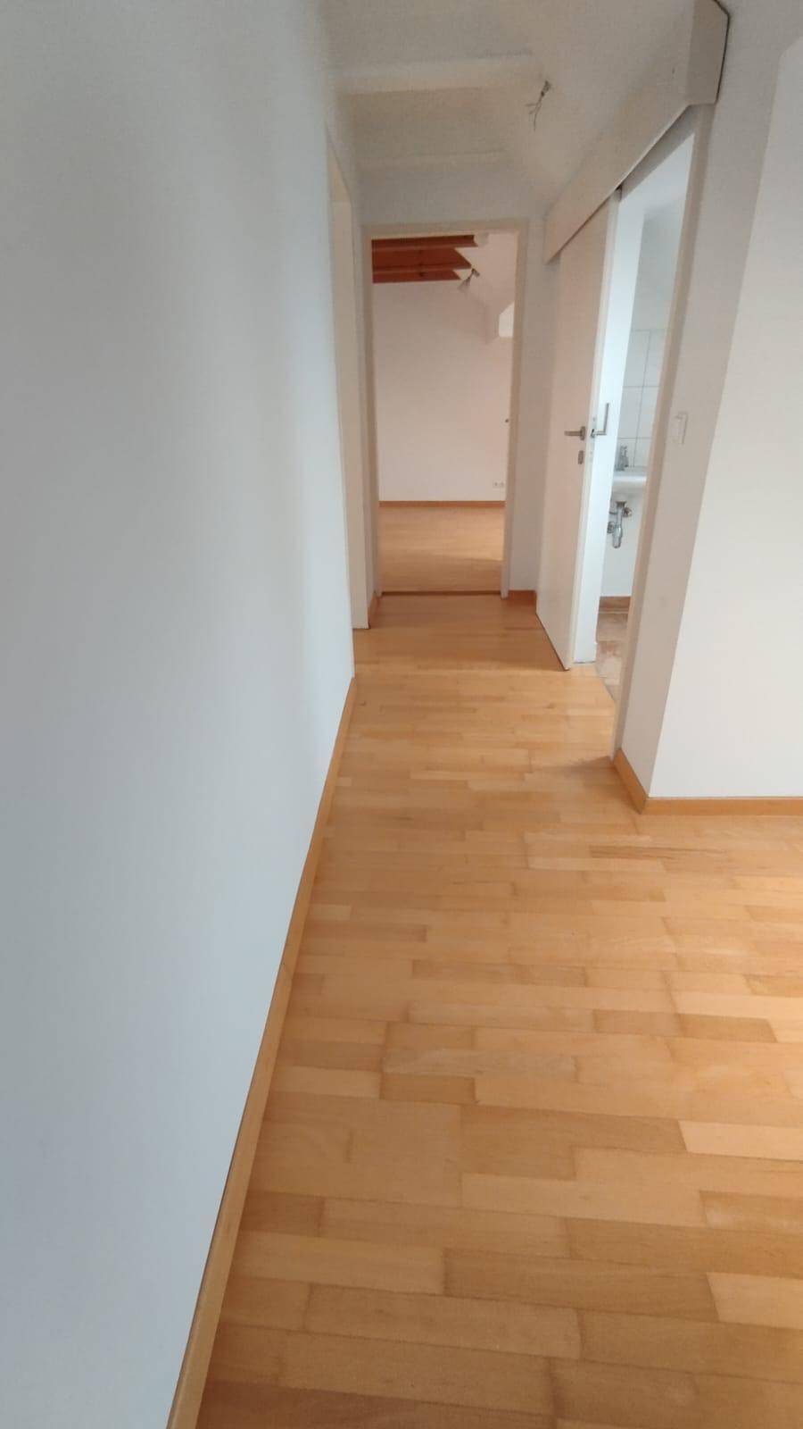 Heller Flur mit Holzparkettboden, der zu weiteren Räumen im Haus führt.