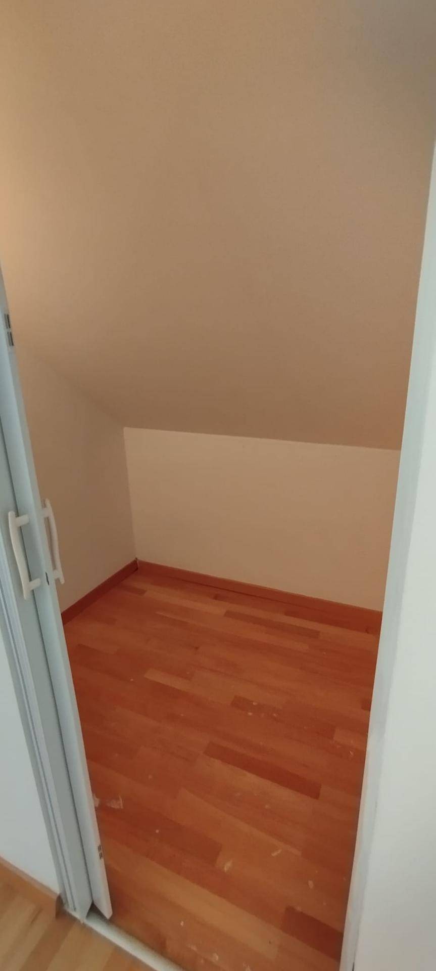 Kleiner Abstellraum im Dachgeschoss mit schrägen Wänden und Holzparkettboden.