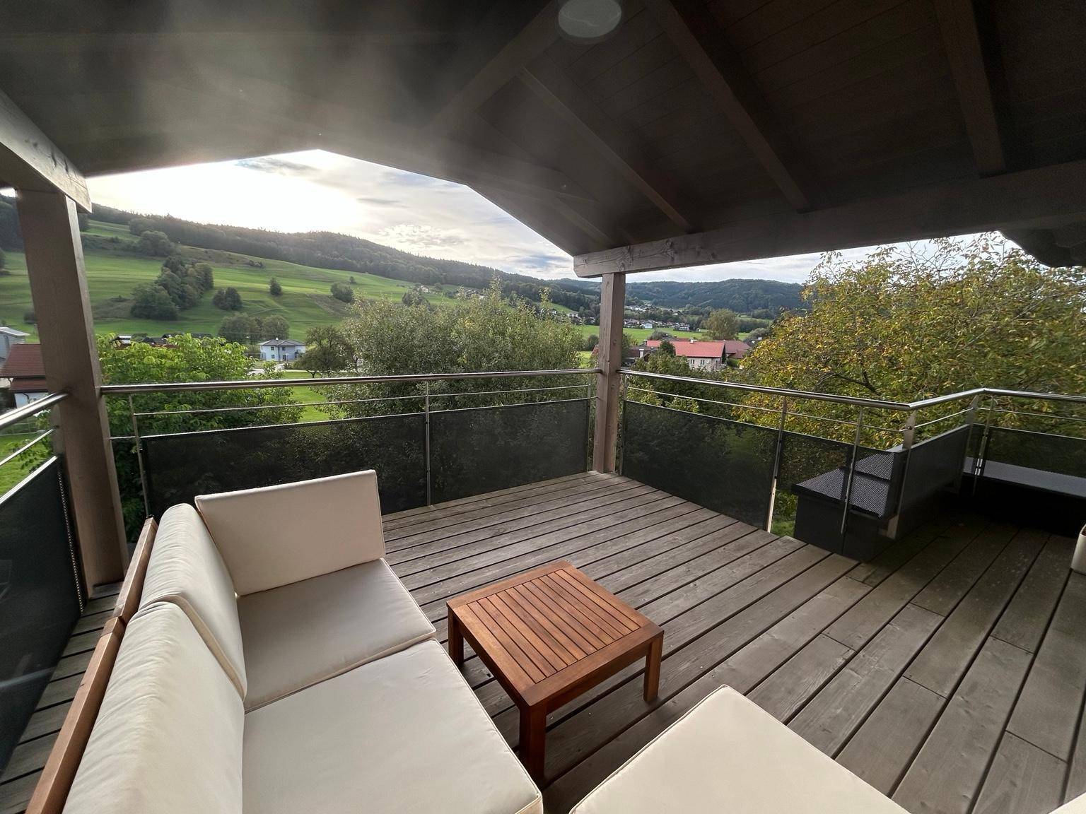 Geräumige überdachte Terrasse mit bequemen Sitzmöbeln und weitem Blick auf die umliegende Landschaft.