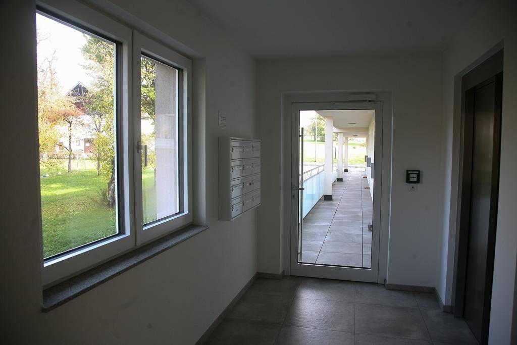 Heller Eingangsbereich mit Fliesenboden, Briefkästen, großem Fenster und Zugang zum Aufzug.