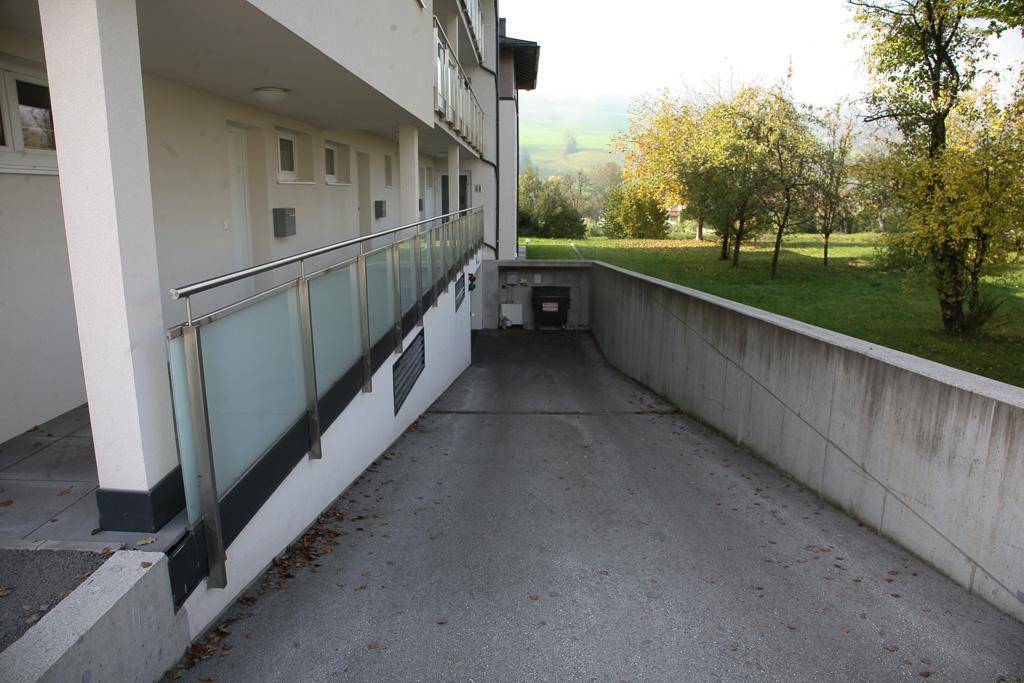 Zufahrt zu einer Tiefgarage neben dem Gebäude mit Grünfläche und Bäumen.