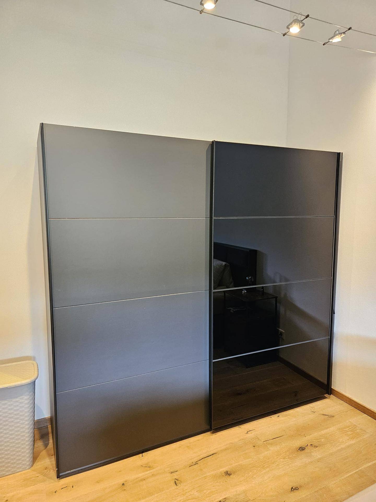 Moderner Kleiderschrank mit Schiebetüren in Grau und Schwarz im Schlafzimmer.