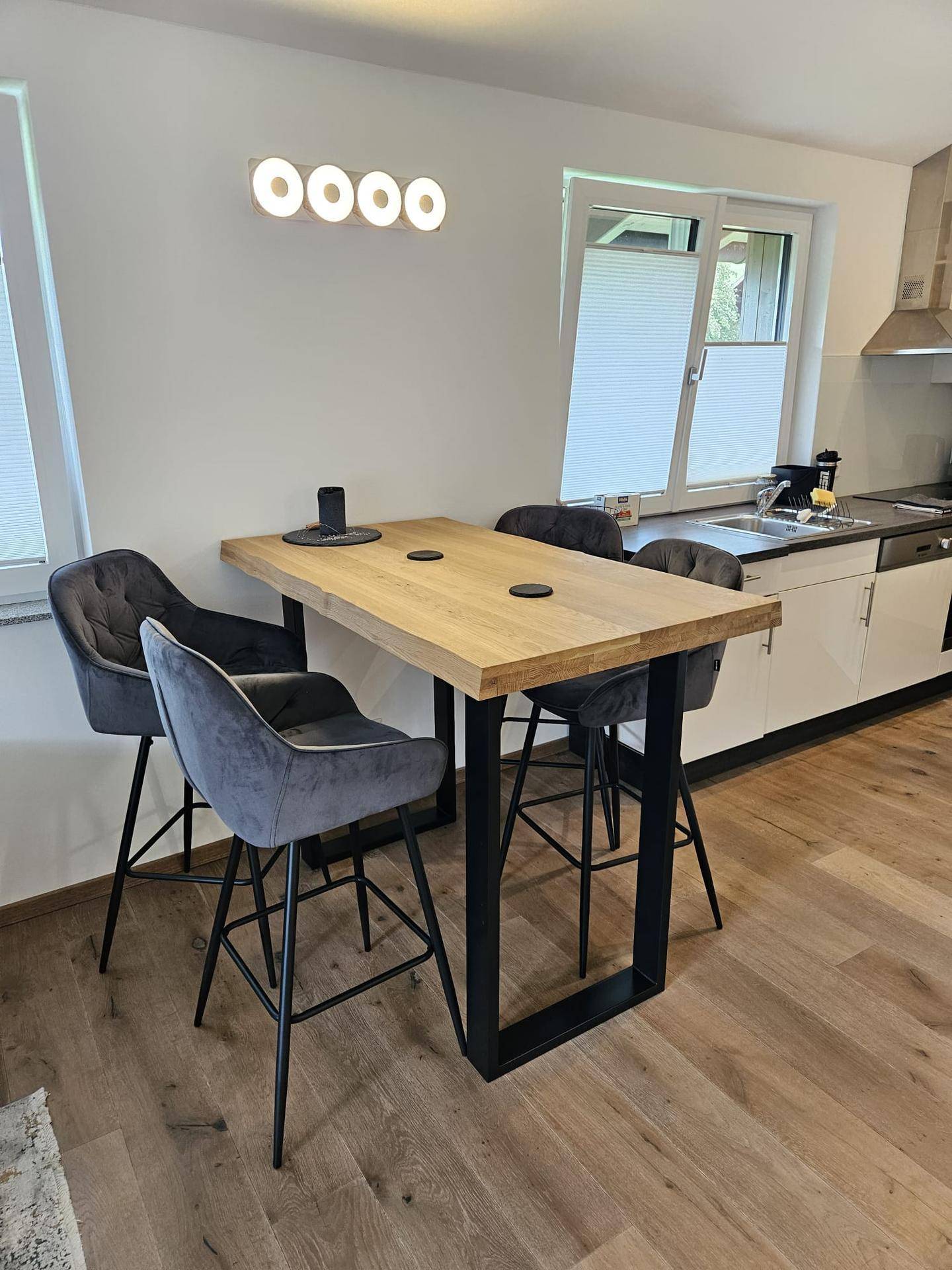 Moderne Küche mit Holztresen, Barhockern und integrierter Spüle unter dem Fenster.