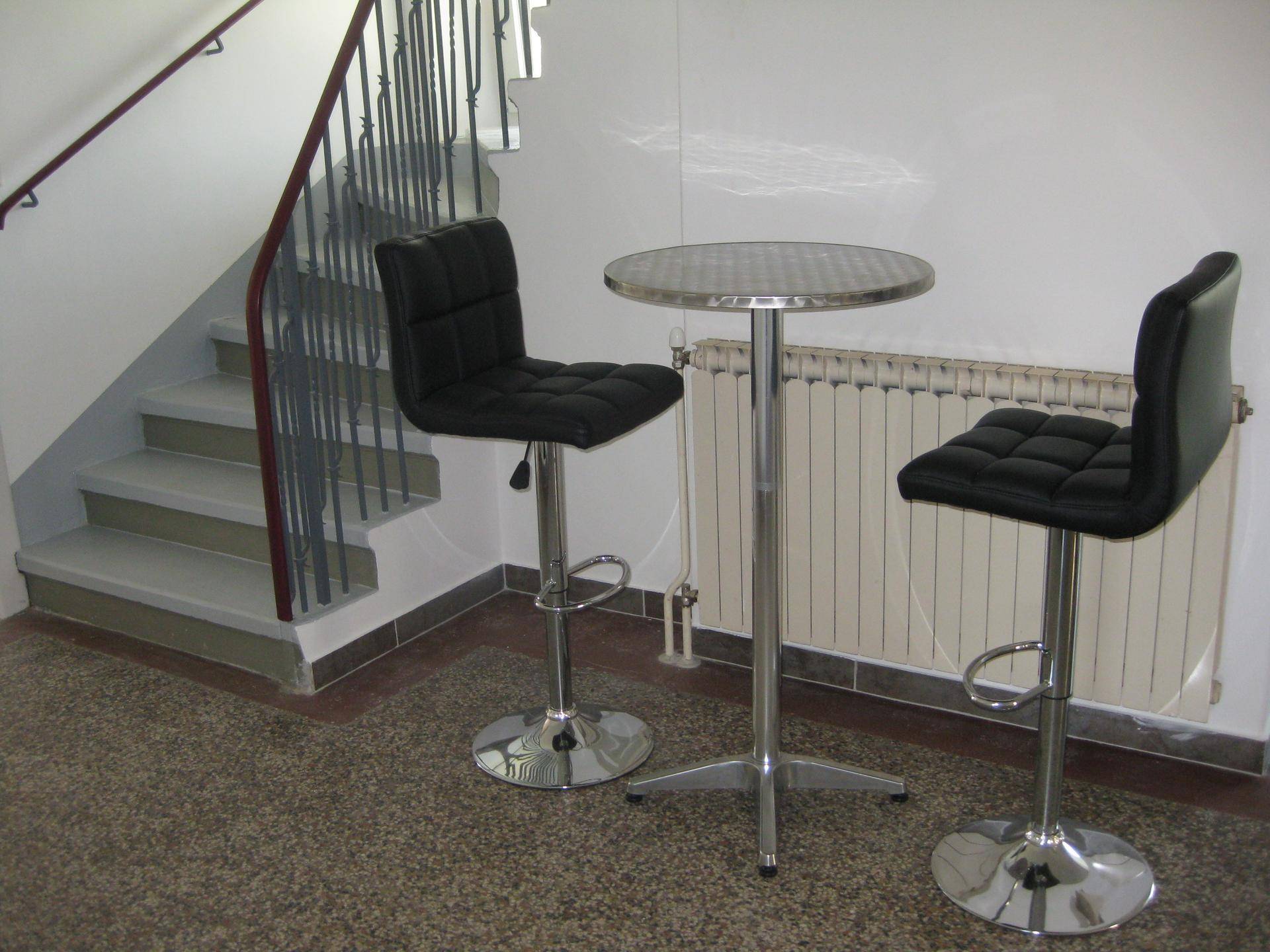 Eingangsbereich mit einer Treppe, einem Stehtisch und zwei Barhockern, ideal für kurze Pausen.