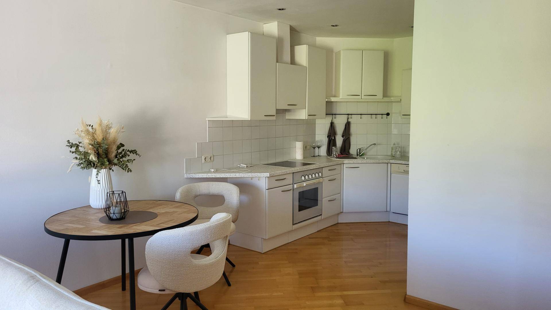 Moderne Einbauküche mit weißen Schränken, Kochfeld und Essbereich.