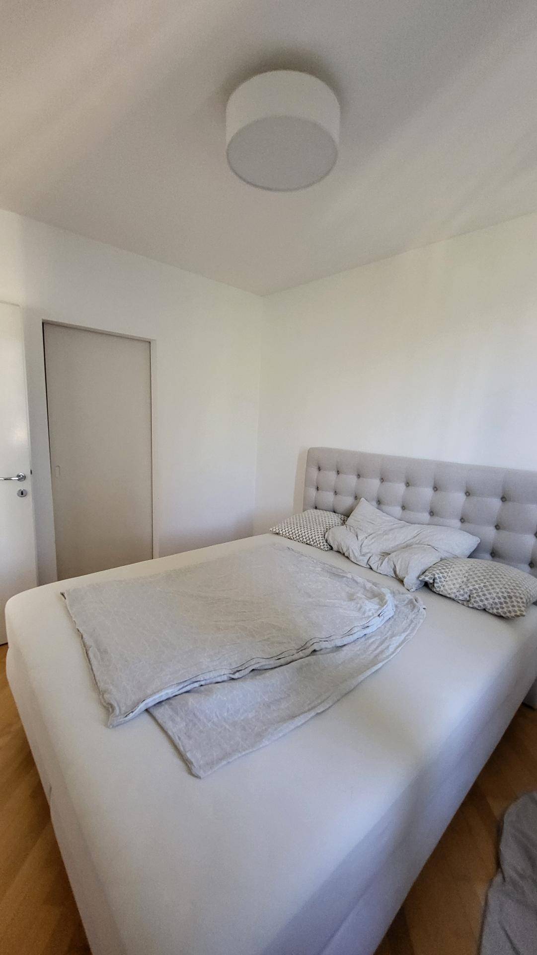 Schlafzimmer mit bequemen Bett und weißer Wandfarbe, bereit zur individuellen Gestaltung.