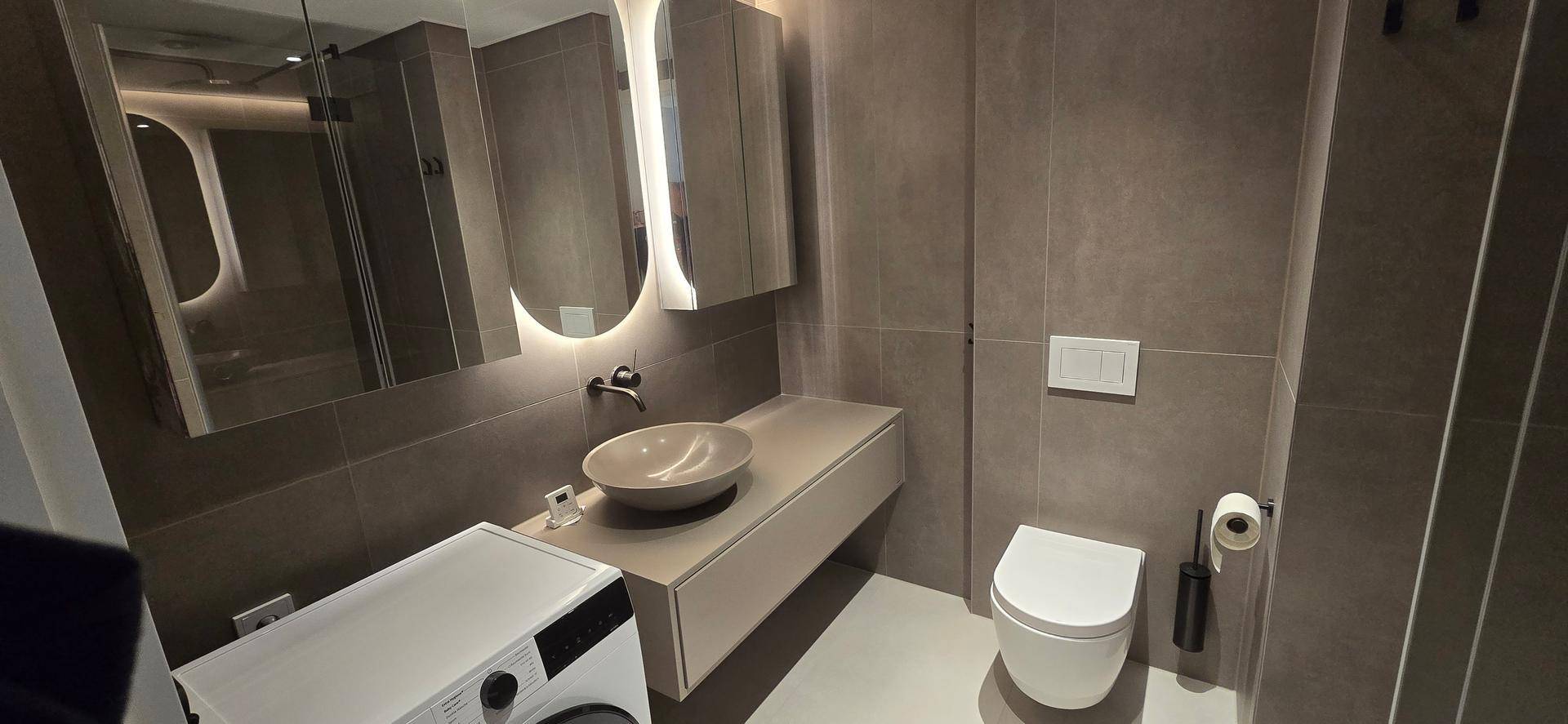 Modernes Badezimmer mit eleganten grauen Fliesen, Aufsatzwaschbecken und wandhängendem WC.