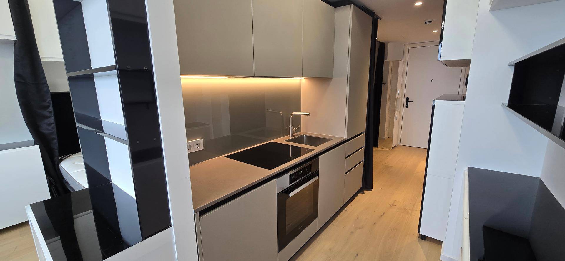Kompakte, moderne Küchenzeile mit integrierten Geräten und heller Holzoptik-Arbeitsplatte.