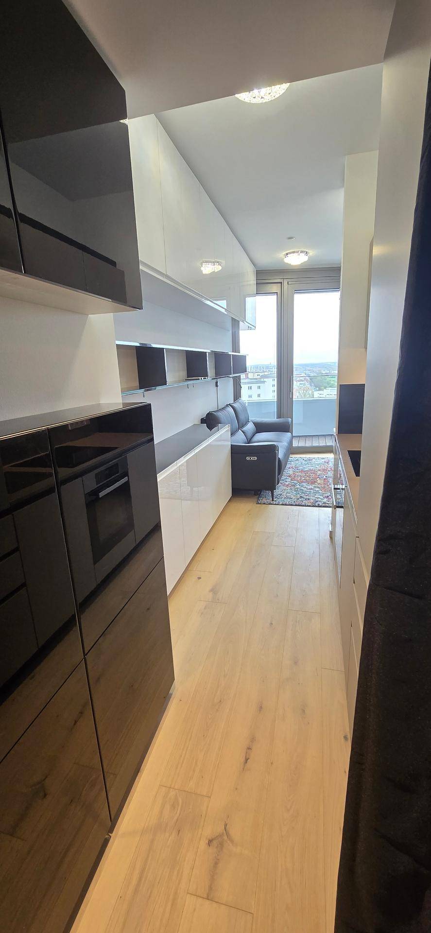 Langer, offener Wohnbereich mit Holzboden, Einbauschränken und Blick auf die Stadt.