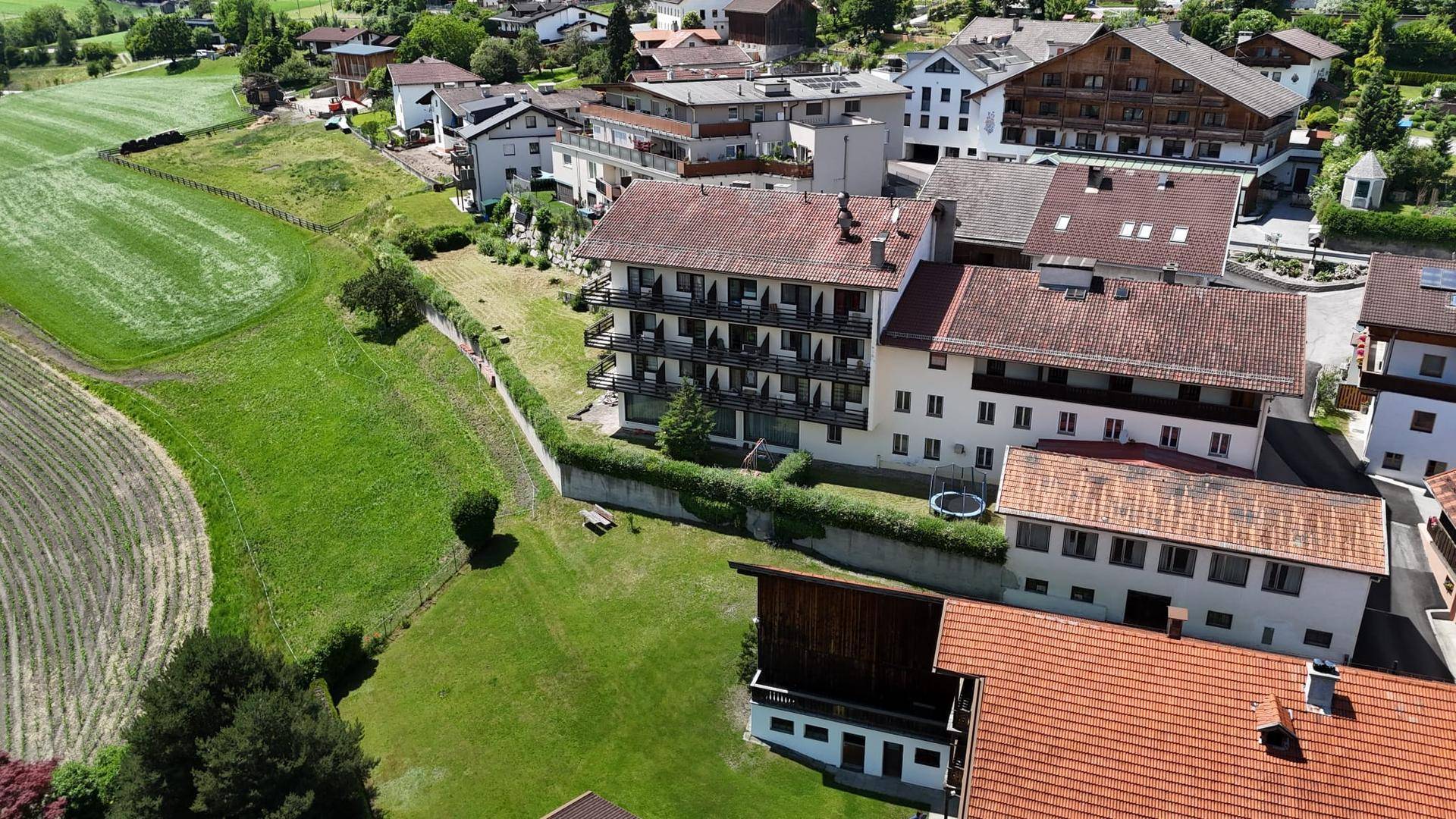 Luftaufnahme von Wohngebäuden mit Balkonen und grünen Wiesen in ländlicher Umgebung.