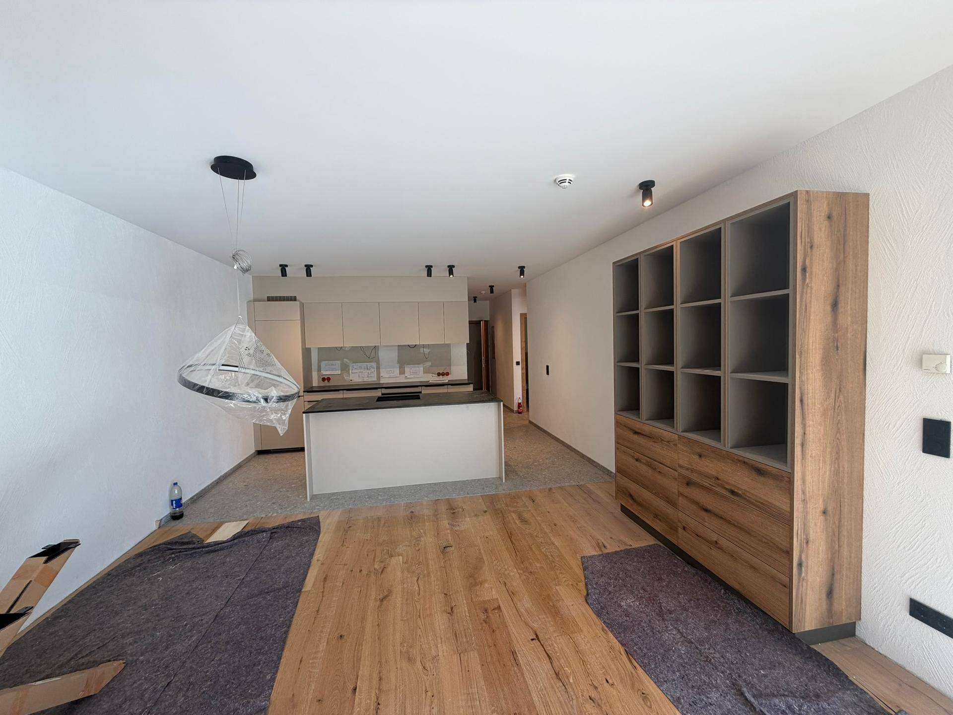 Offener Wohn- und Essbereich mit moderner Küche, Kücheninsel und Holzboden, noch im Bau.