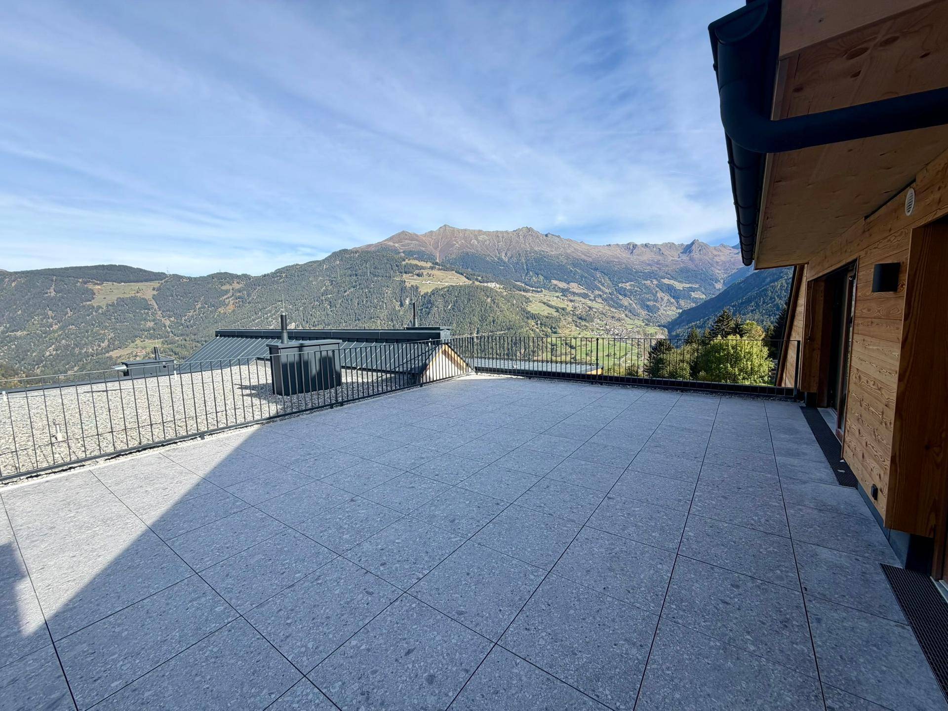 Weitläufige Terrasse mit atemberaubendem Panoramablick auf die Alpen und die grüne Umgebung.