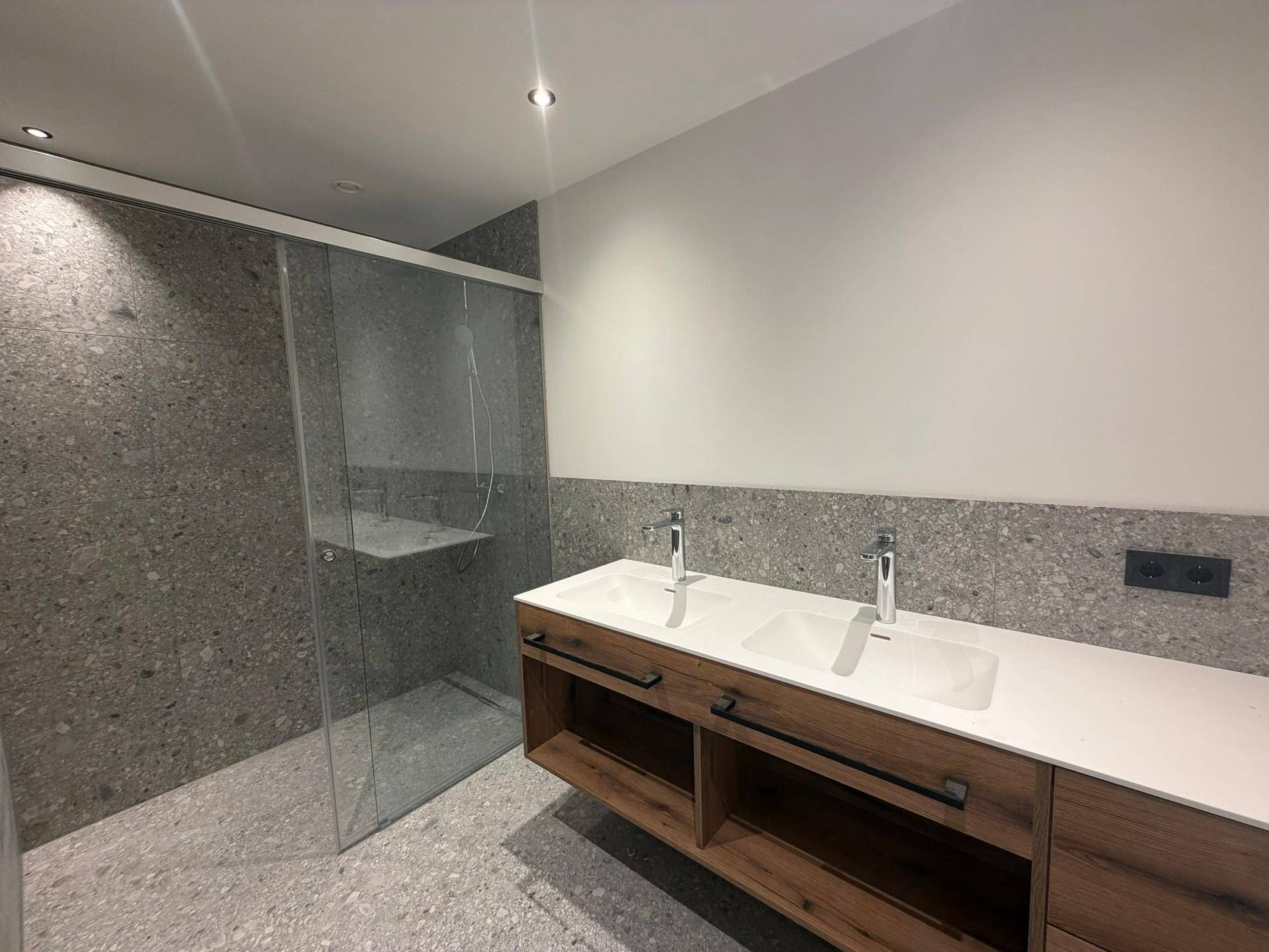 Modernes Badezimmer mit Doppelwaschbecken, großer begehbarer Dusche und stilvollen grauen Fliesen.