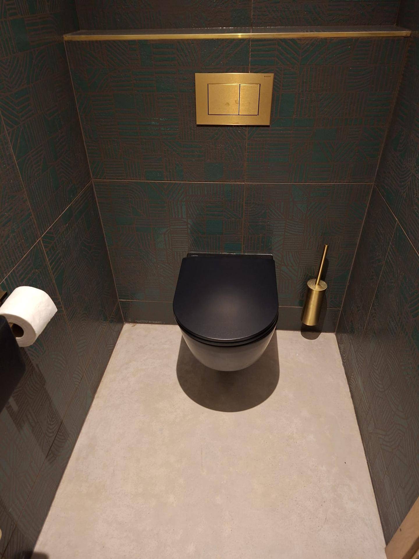 Modernes Gäste-WC mit dunklen Fliesen, wandhängendem WC und goldenen Armaturen.