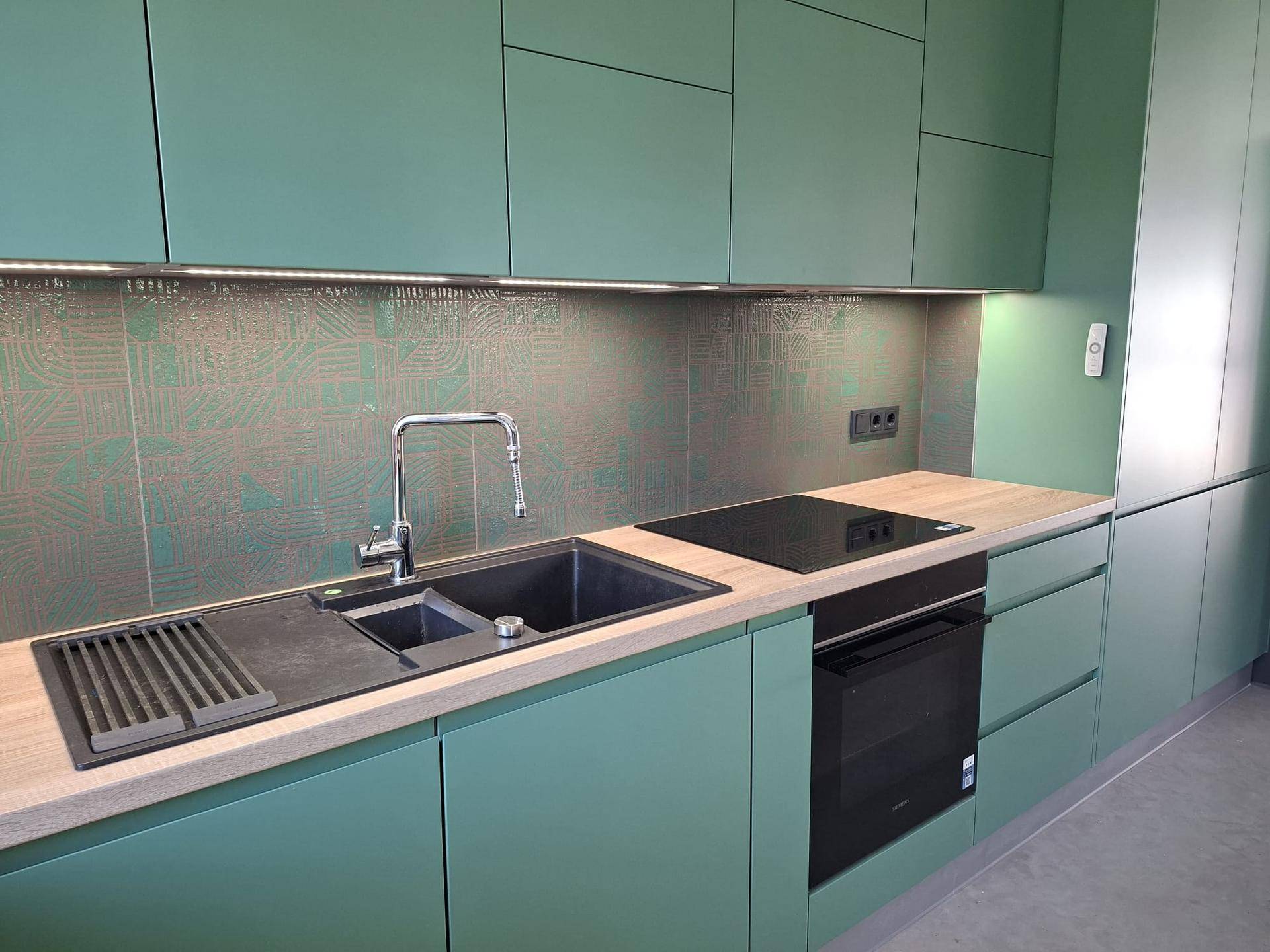 Moderne Einbauküche mit mintgrünen Schränken, Holzoptik-Arbeitsplatte und integrierten Geräten.