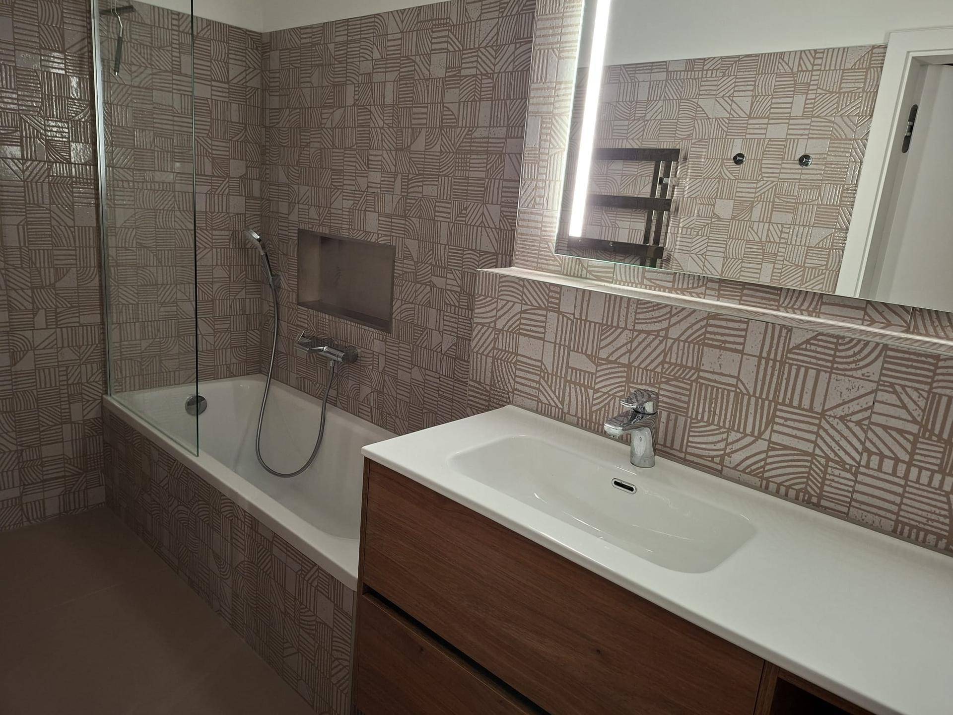Helles Badezimmer mit Badewanne, Duschabtrennung und großem Spiegel über dem Waschtisch.