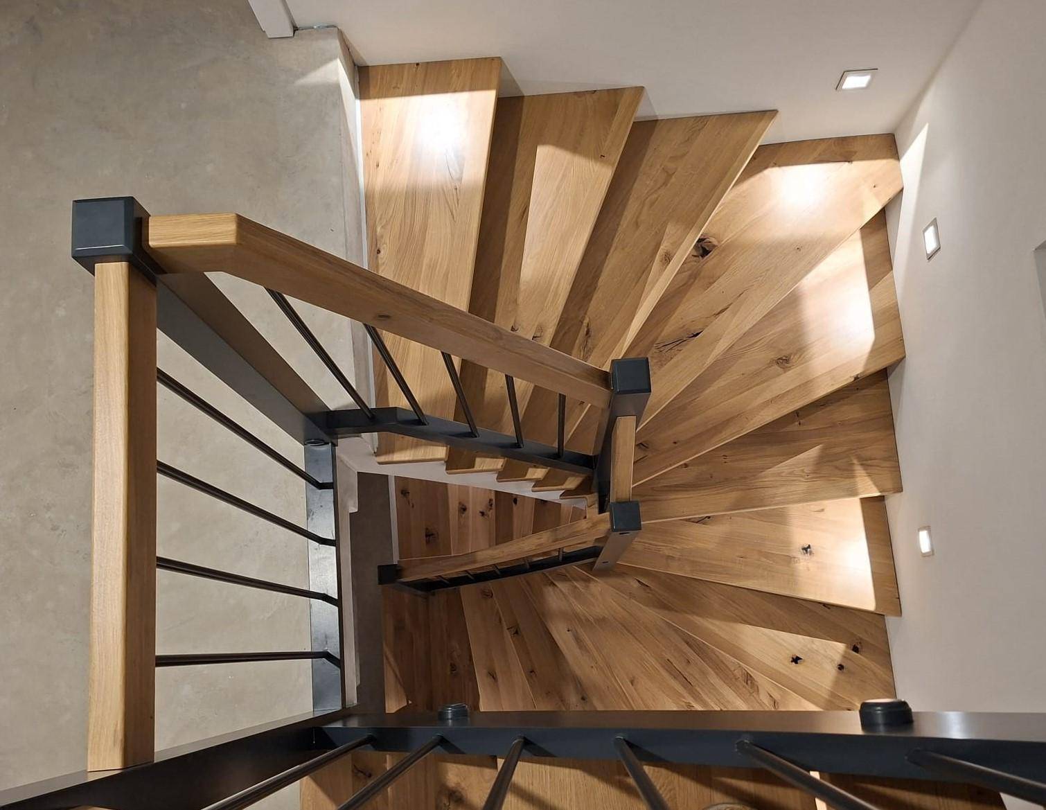 Elegante Holztreppe mit schwarzem Geländer, die die verschiedenen Etagen verbindet.