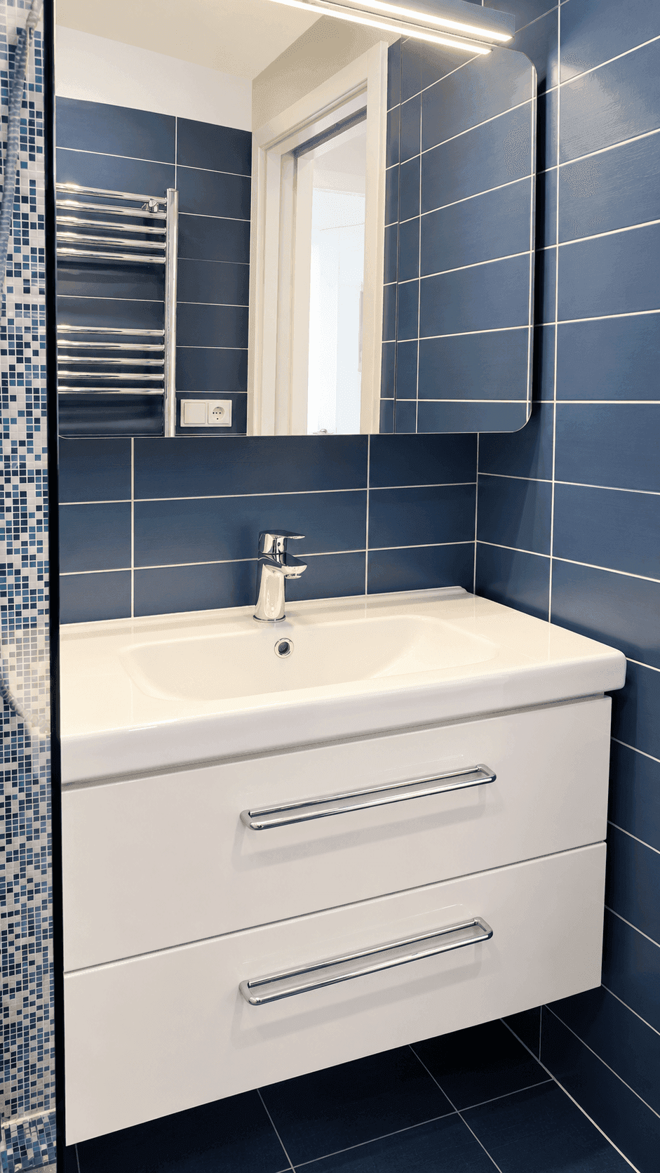 Modernes Badezimmer mit blauen Fliesen, Waschtischunterschrank und beheiztem Handtuchhalter.