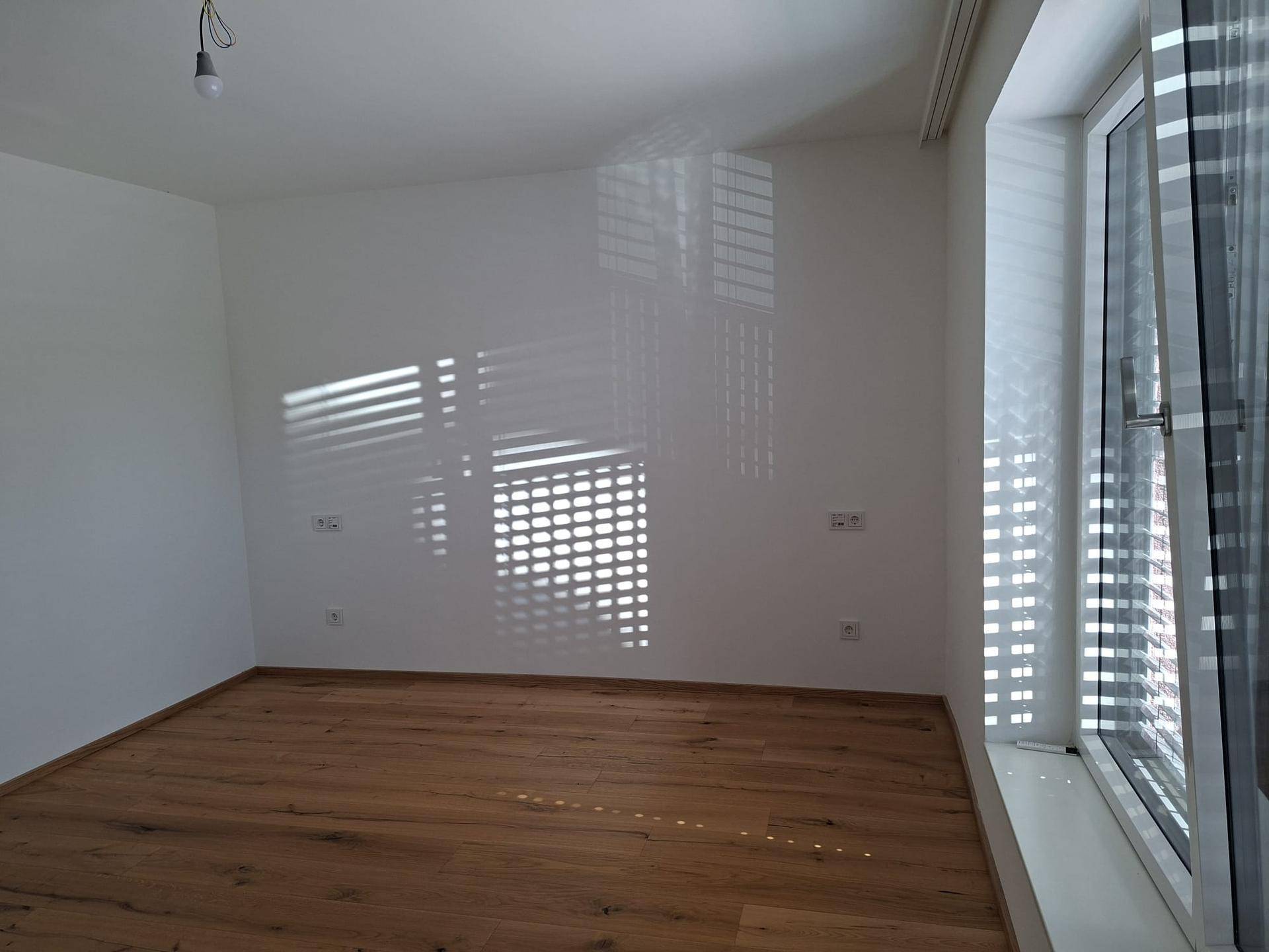 Geräumiges Zimmer mit Holzboden, weißen Wänden und viel natürlichem Lichteinfall.