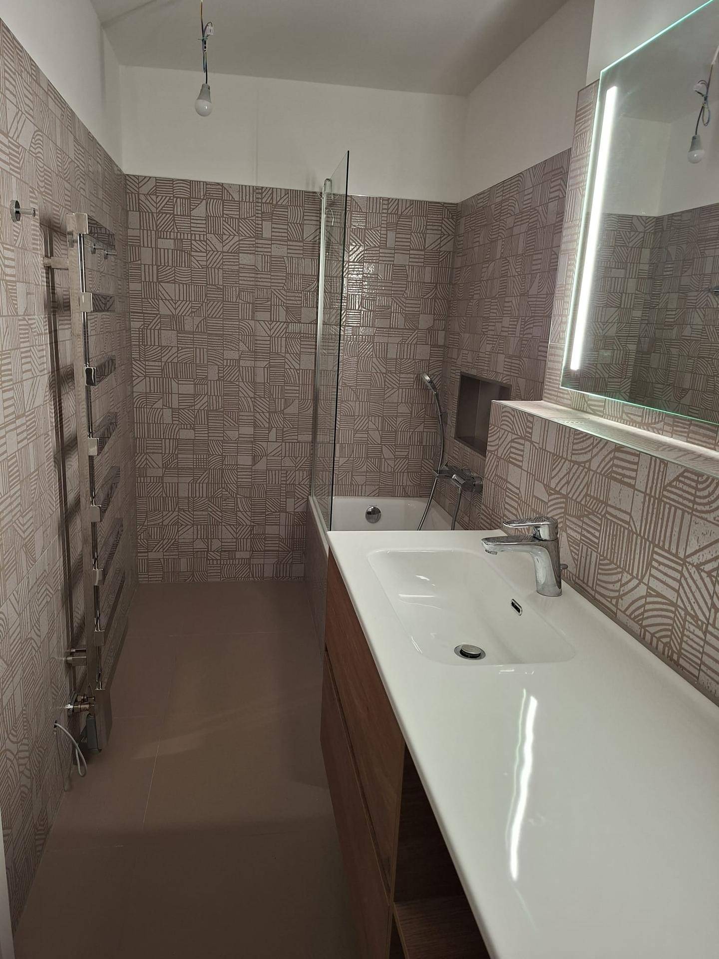 Modernes Badezimmer mit Badewanne, Waschtisch und gemusterten Fliesen an den Wänden.