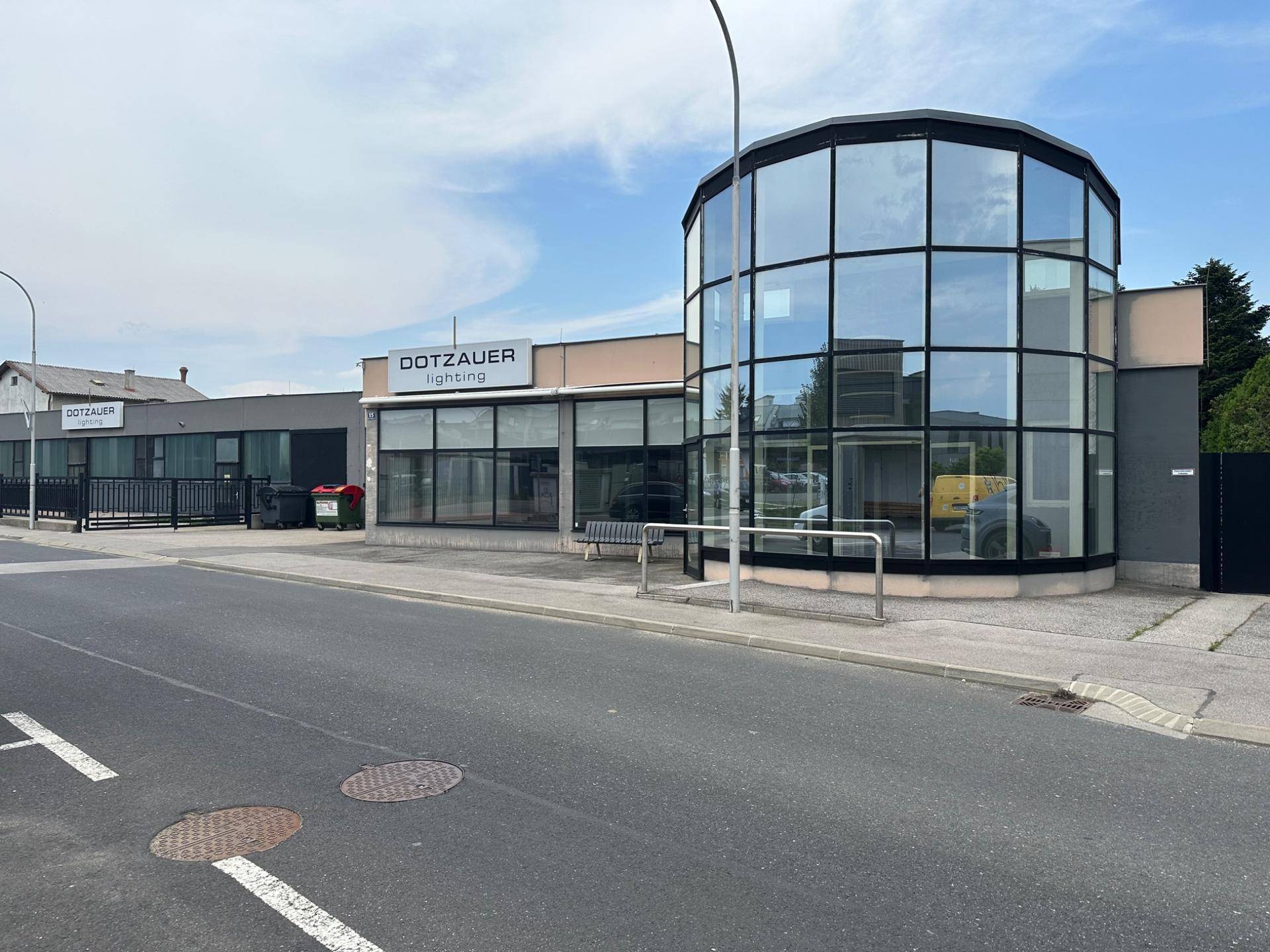 Modernes Geschäftsgebäude mit einer markanten runden Glasfassade und großen Schaufenstern zur Straße hin.
