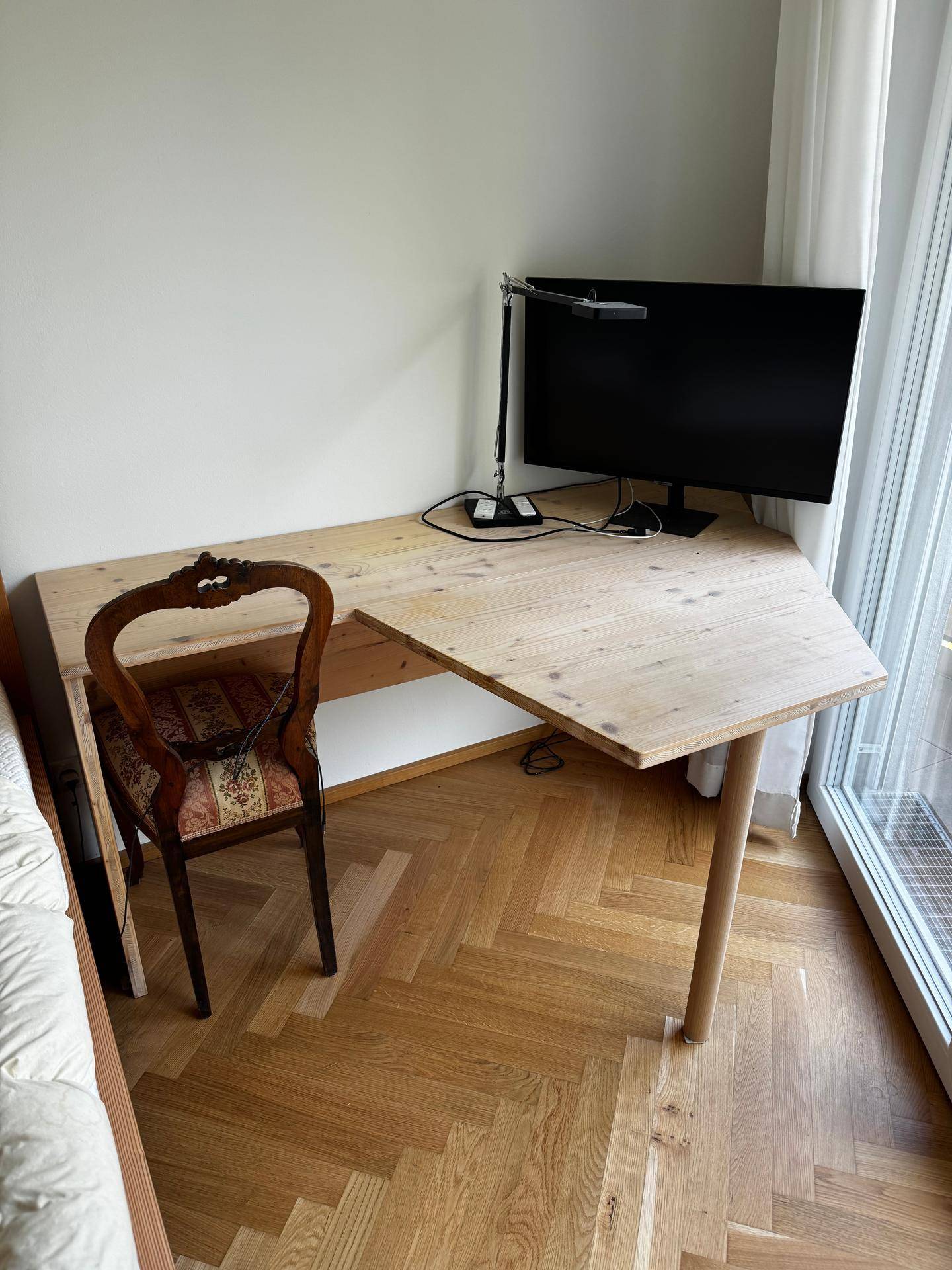 Arbeitsbereich im Schlafzimmer mit einem Holzschreibtisch und großem Fenster für viel Tageslicht.