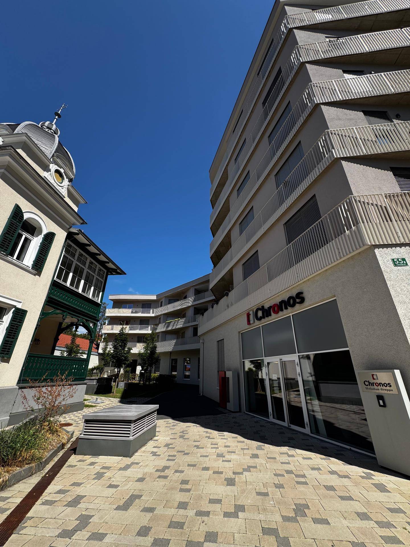 Ansicht des modernen Wohnkomplexes mit Innenhof und angrenzendem historischen Gebäude.