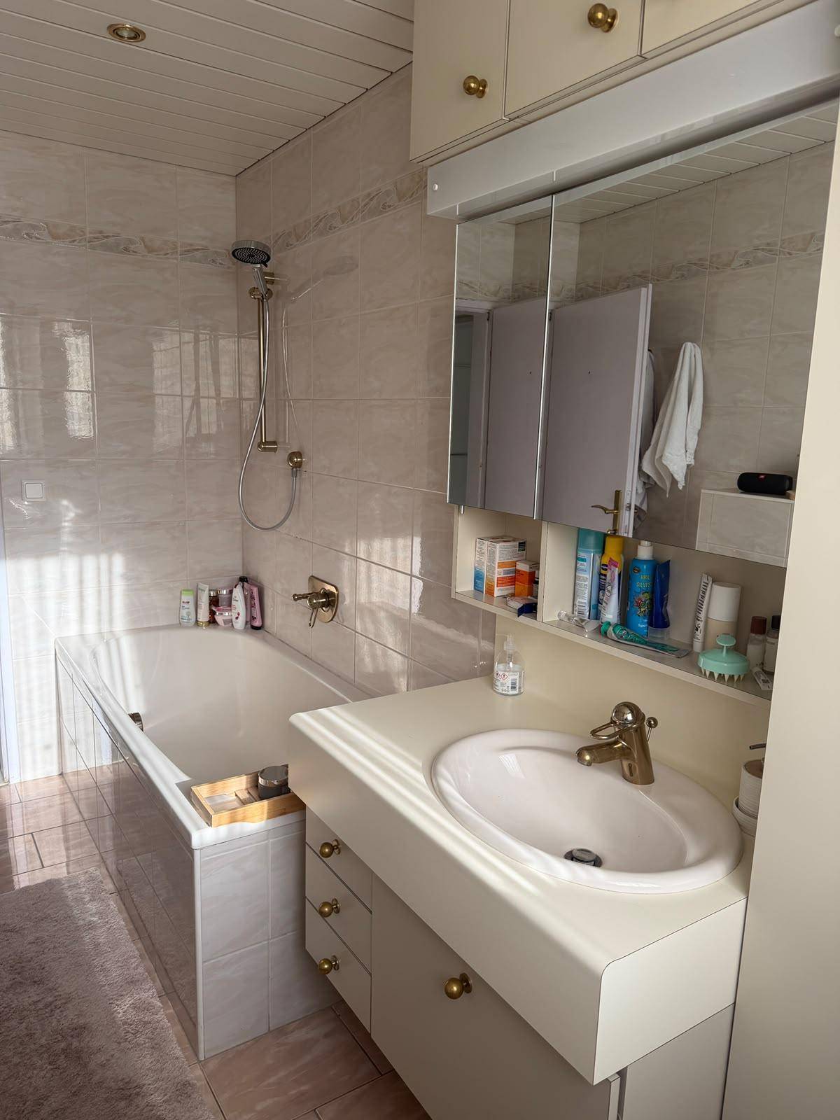 Helles Badezimmer mit Badewanne, Waschbecken und Spiegelschrank.
