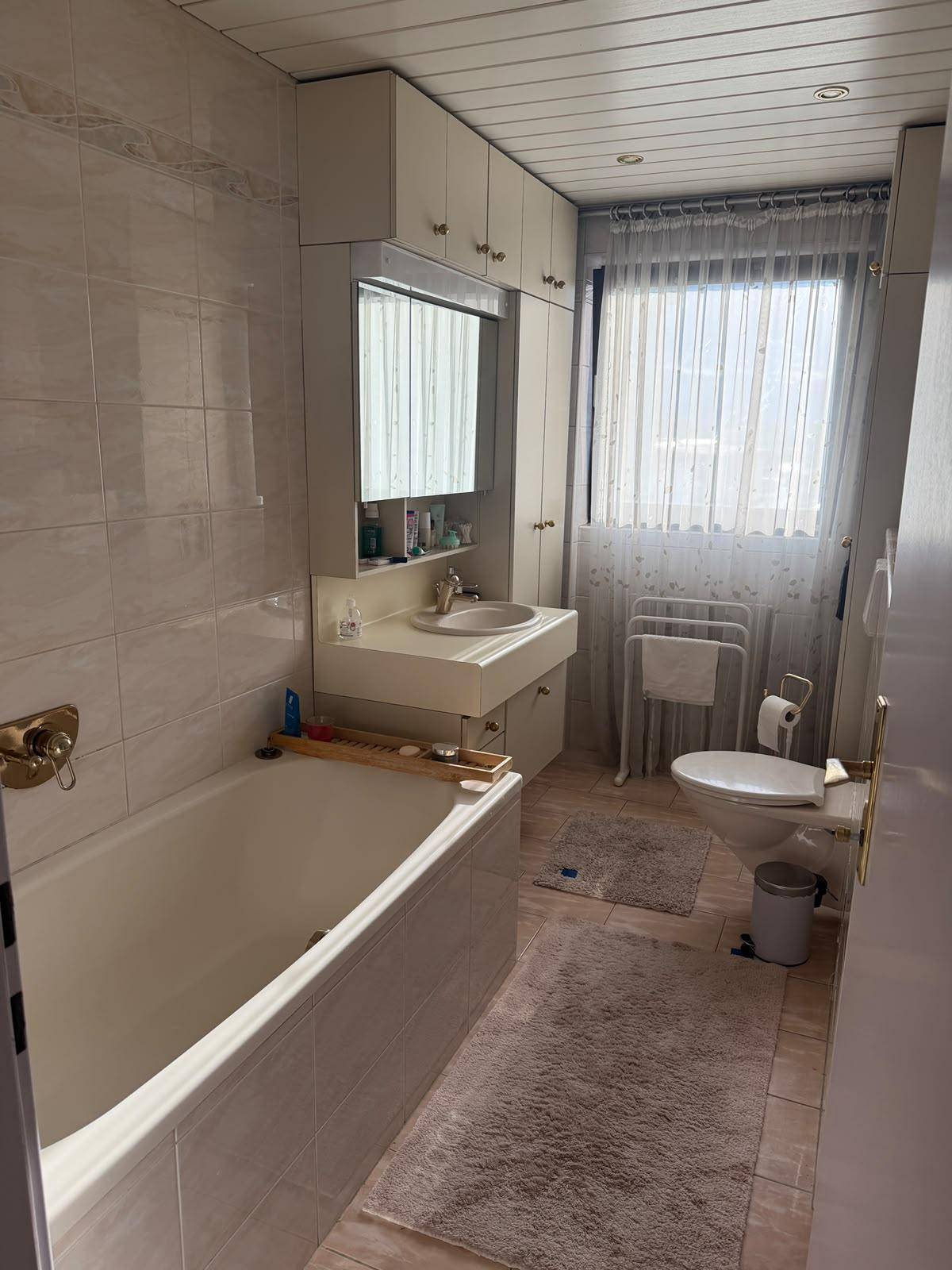 Badezimmer mit Badewanne, Waschbecken, WC und Fenster für Tageslicht.