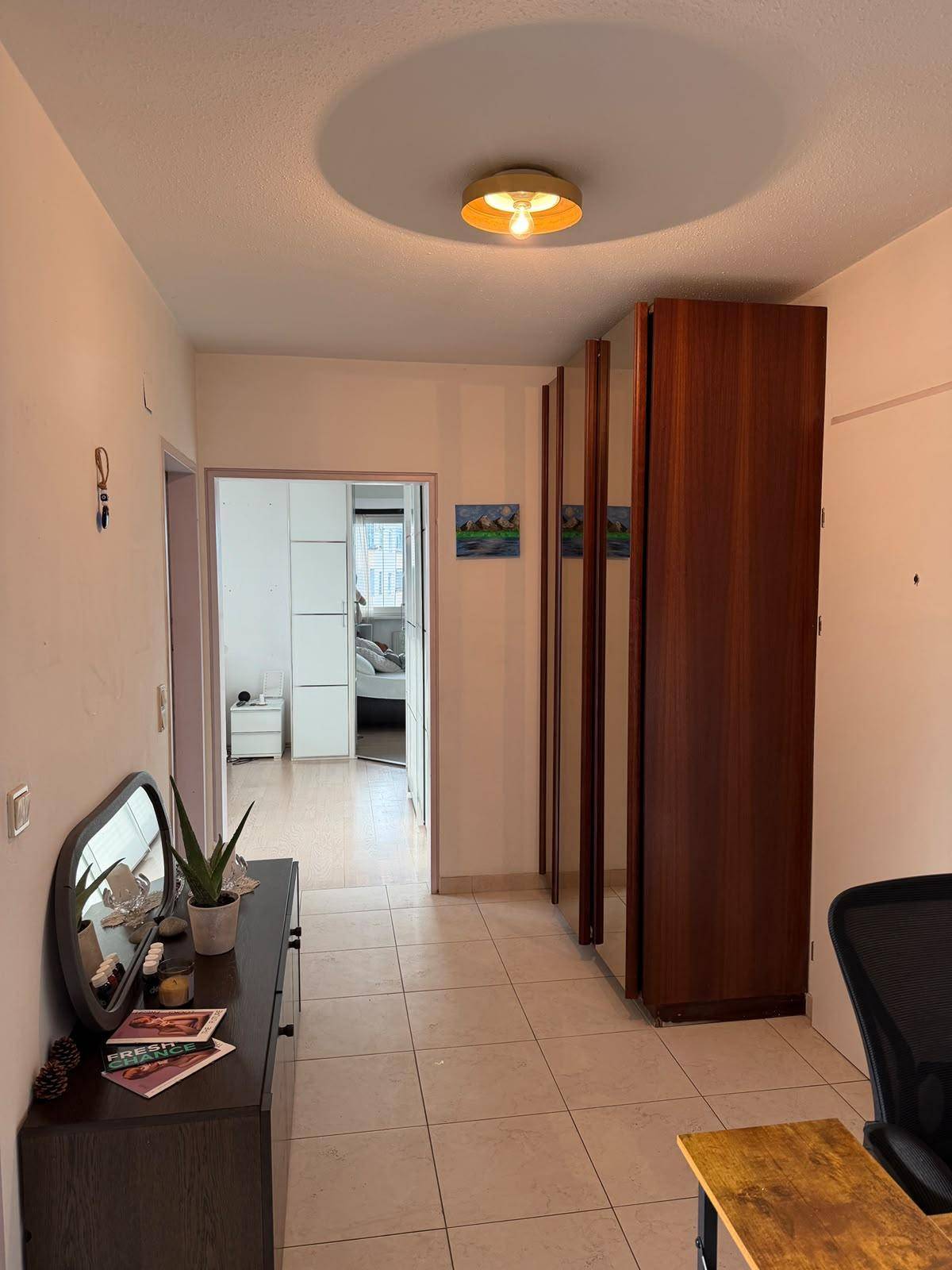 Heller Flur mit Fliesenboden, Spiegelschrank und Zugang zu weiteren Räumen.