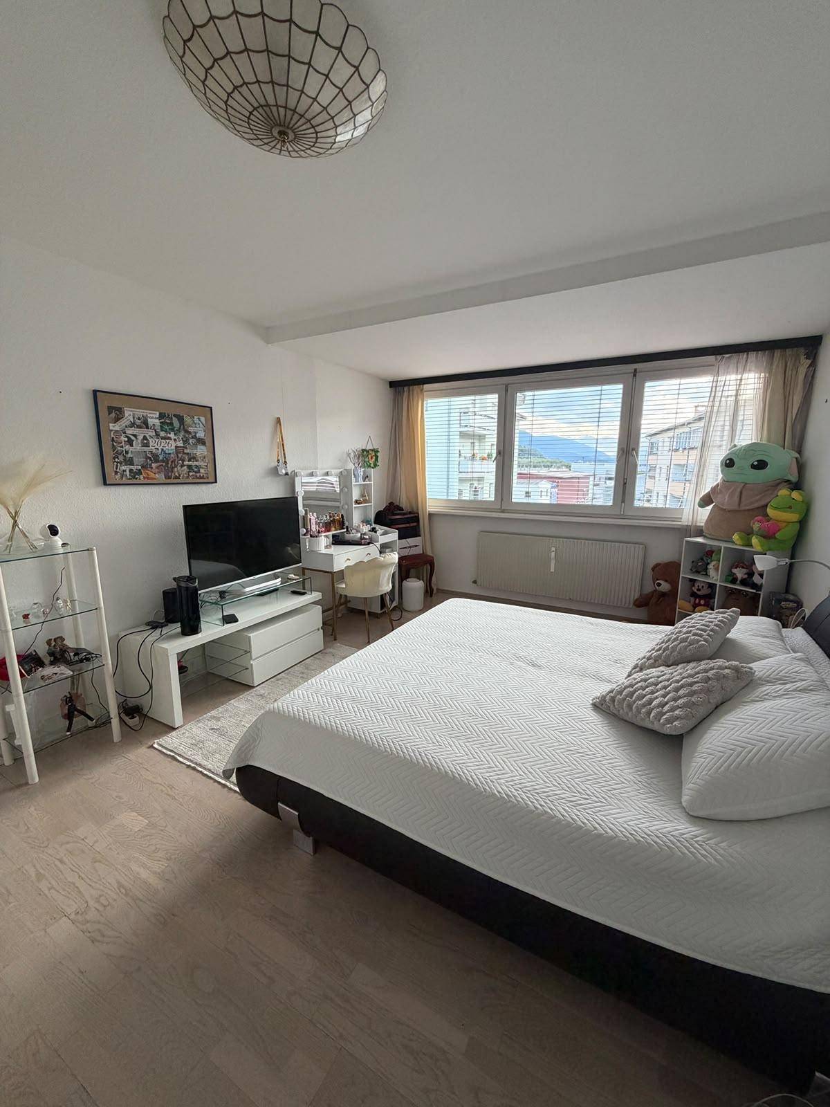 Helles Schlafzimmer mit Doppelbett, Schreibtisch und Blick auf die Umgebung.
