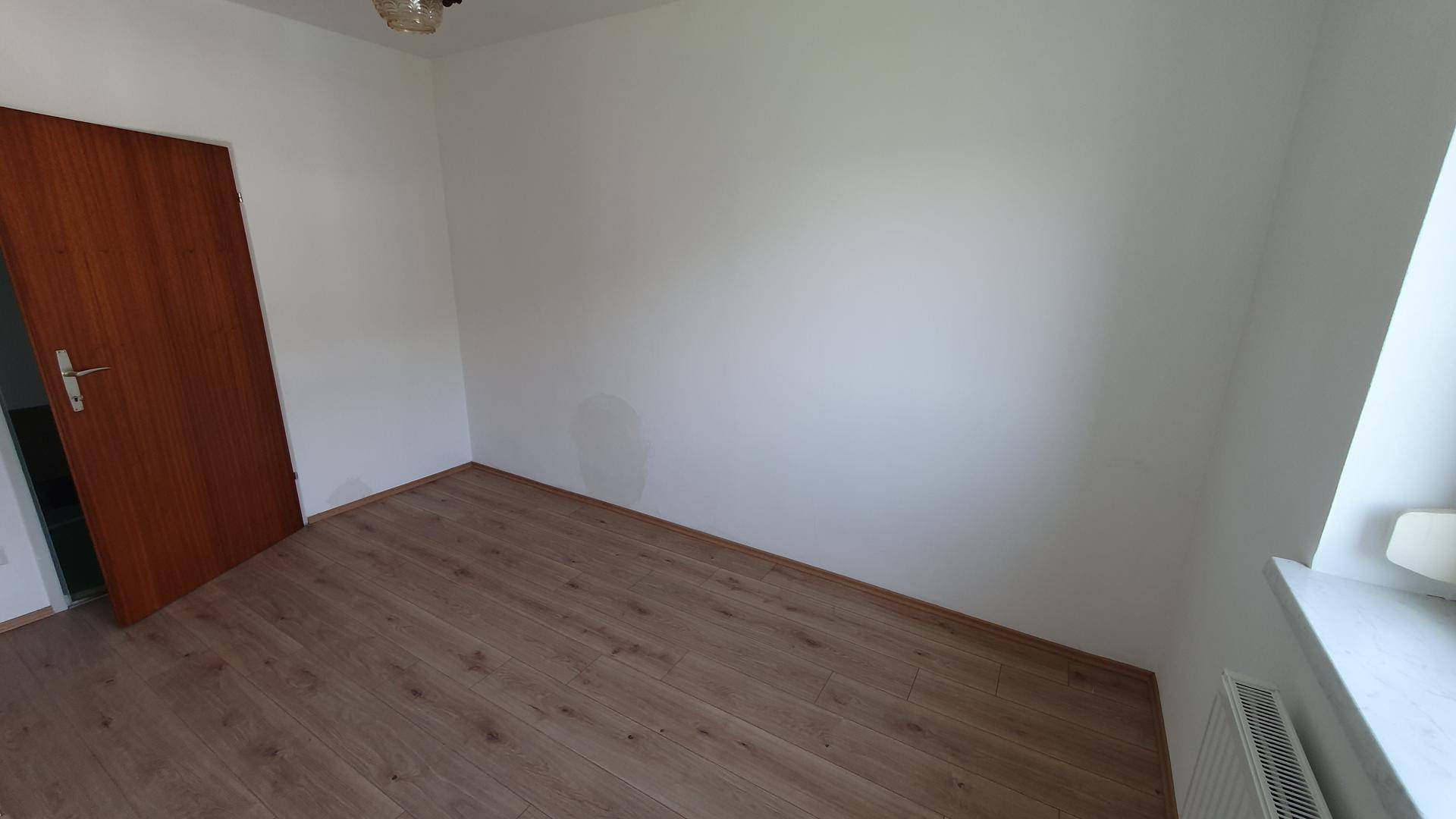 Helles Zimmer mit Holzboden und weiß gestrichenen Wänden, bietet eine neutrale Basis für individuelle Gestaltung.