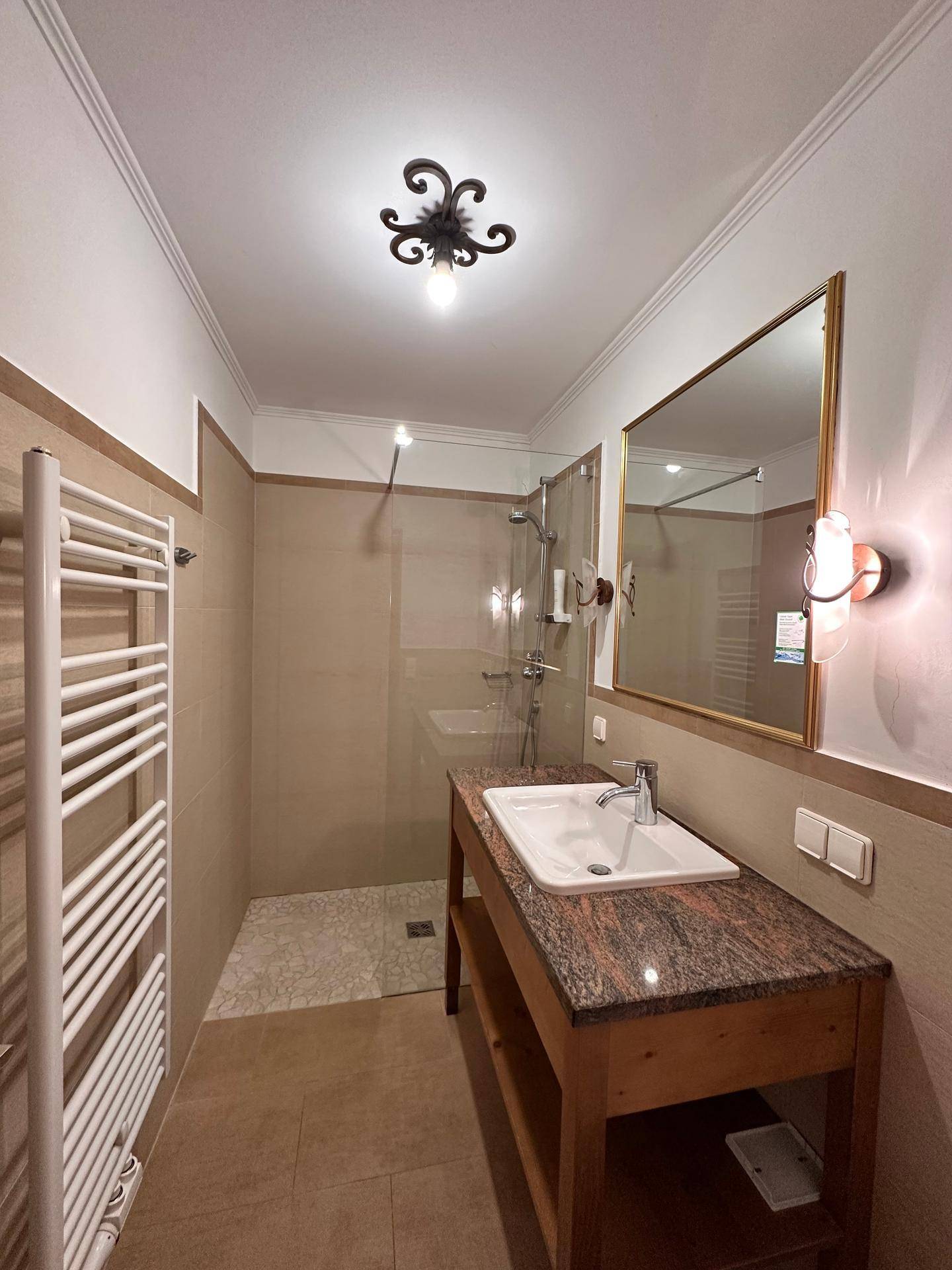 Modernes Badezimmer mit Duschkabine, Waschtisch mit Granitplatte und Handtuchheizkörper.