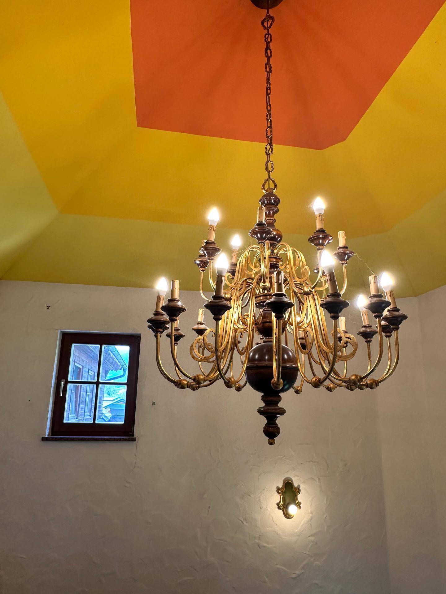 Decke mit gelb-orangem Anstrich und einem opulenten Kronleuchter in einem traditionellen Raum.
