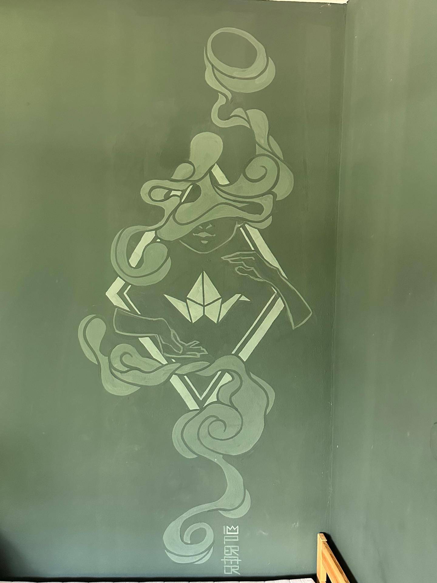 Wandgemälde mit abstrakten Figuren und Mustern auf einer olivgrünen Wand.
