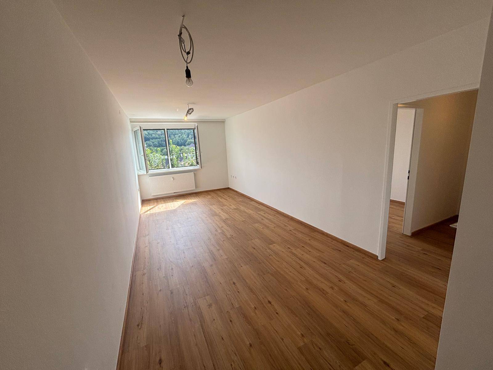 Geräumiges Zimmer mit Laminatboden und einem Fenster, das viel Tageslicht hereinlässt.