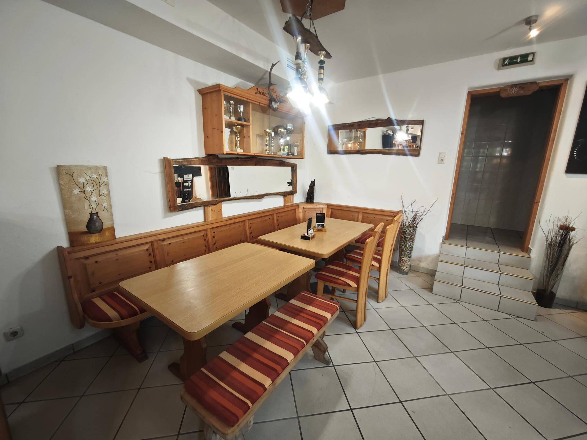 Traditionelle Essecke mit Holzbänken, Tischen und Spiegeln, ideal für gesellige Runden.