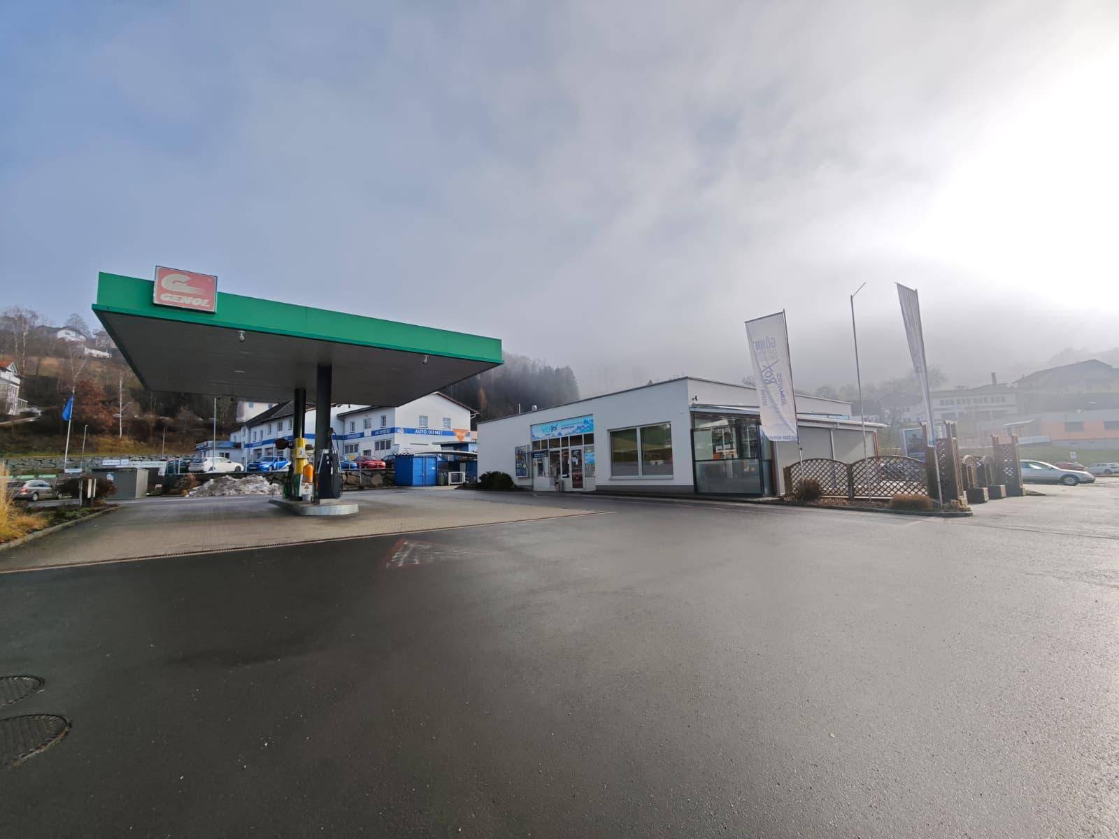 Außenansicht der Tankstelle und des Bistros an einem bewölkten Tag mit weitem Vorplatz.