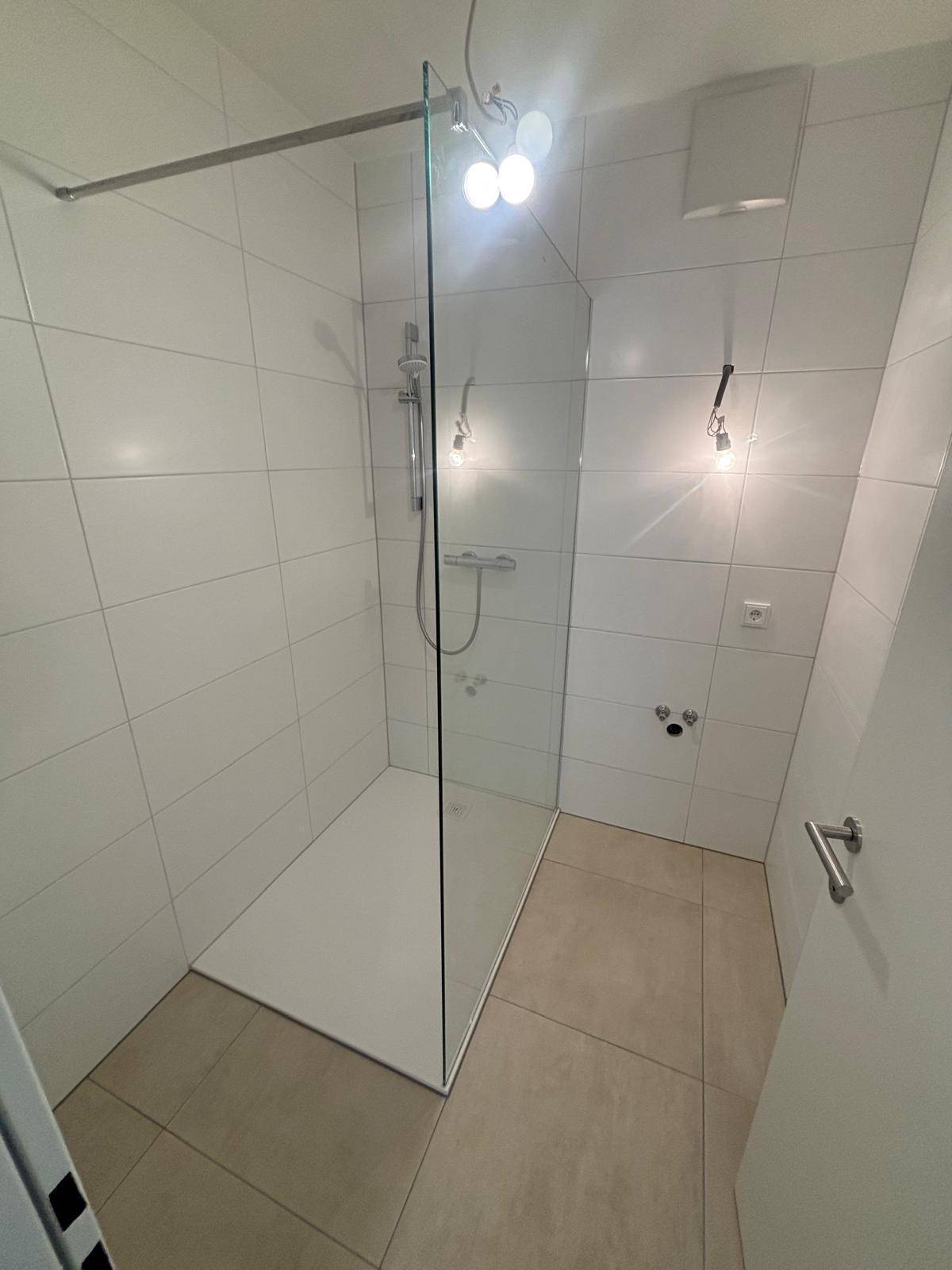 Modernes Badezimmer mit einer geräumigen, ebenerdigen Dusche und hellen Fliesen.