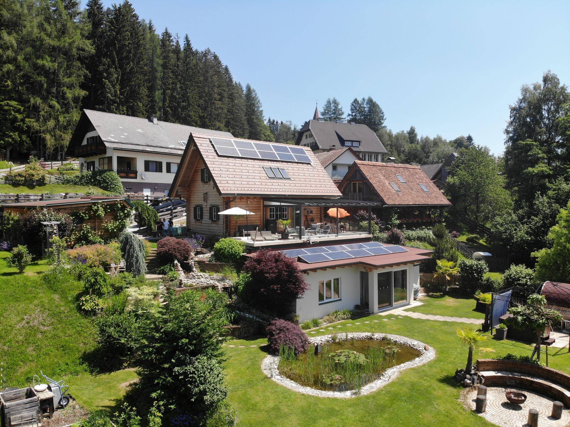 Luftaufnahme des Anwesens mit Haupthaus, Nebengebäuden, großem Garten und Photovoltaikanlage.