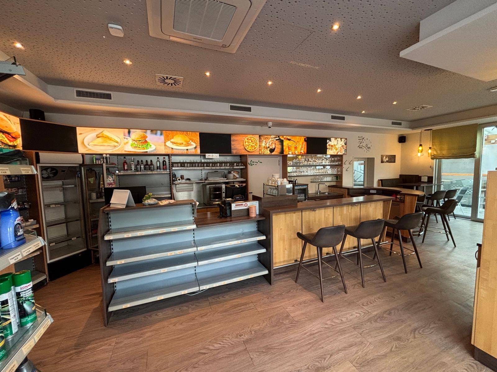 Weitläufiger Bistrobereich mit Theke, Regalen für Produkte und Zugang zu einem überdachten Außenbereich.