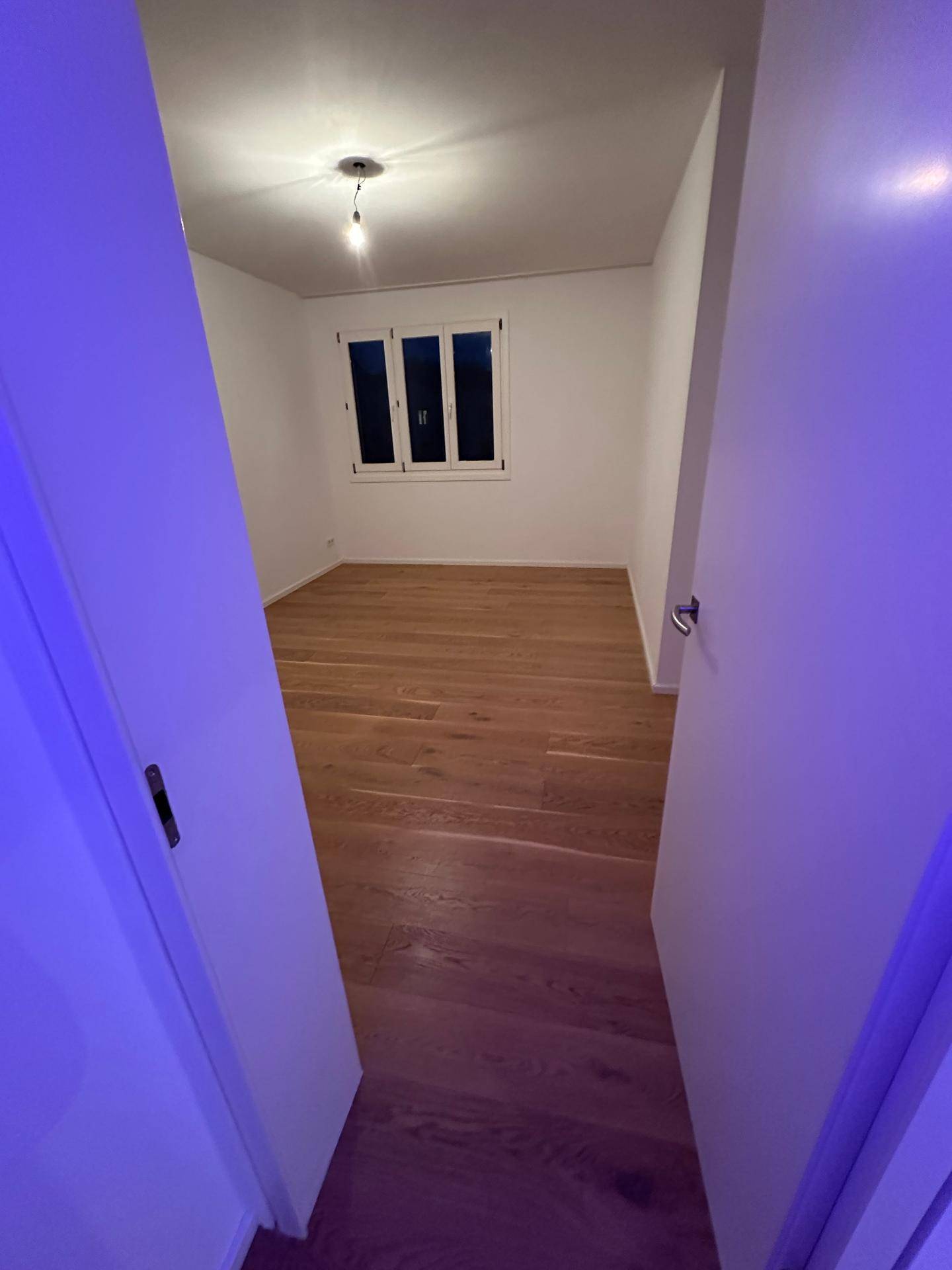 Leeres Schlafzimmer mit neuem Holzboden und Fenster.