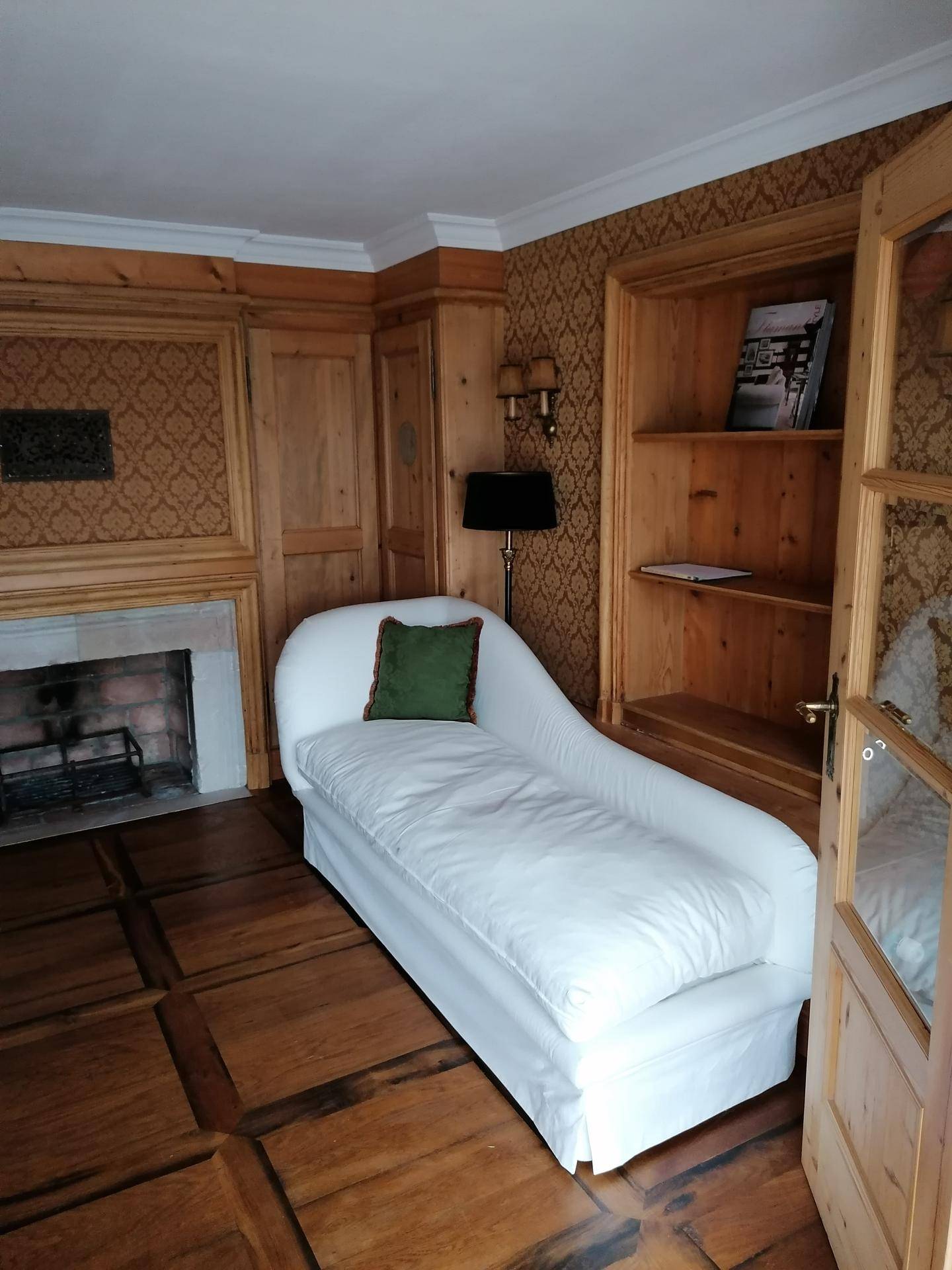Gemütliches Zimmer mit Holztäfelung, Kamin und einer eleganten Chaiselongue für Entspannung.